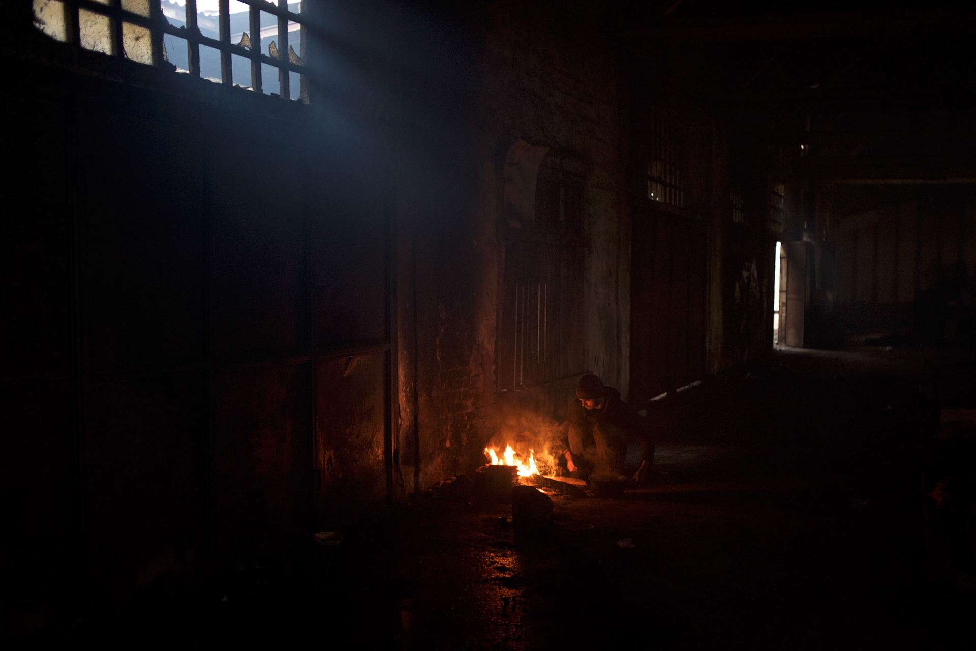 Sadeq, a 13 year old afghan migrant, tends to a fire in one of the abandoned warehouses in central Belgrade, used in recent months as shelter for hundreds of migrants en route to Western Europe.