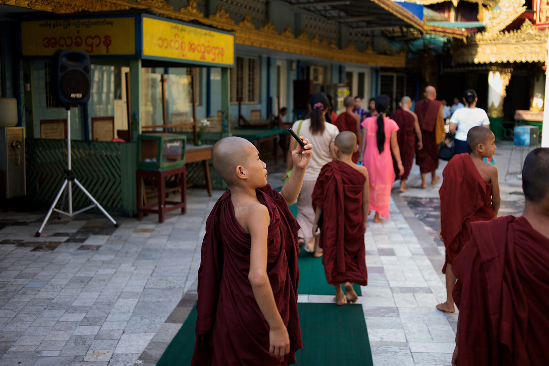 May 09, 2013 - Yangon, Myanmar: A Buddhist novice uses his mobile phone to take photographs of a shrine at Sule Pagoda in central Yangon. CREDIT: Paulo Nunes dos Santos