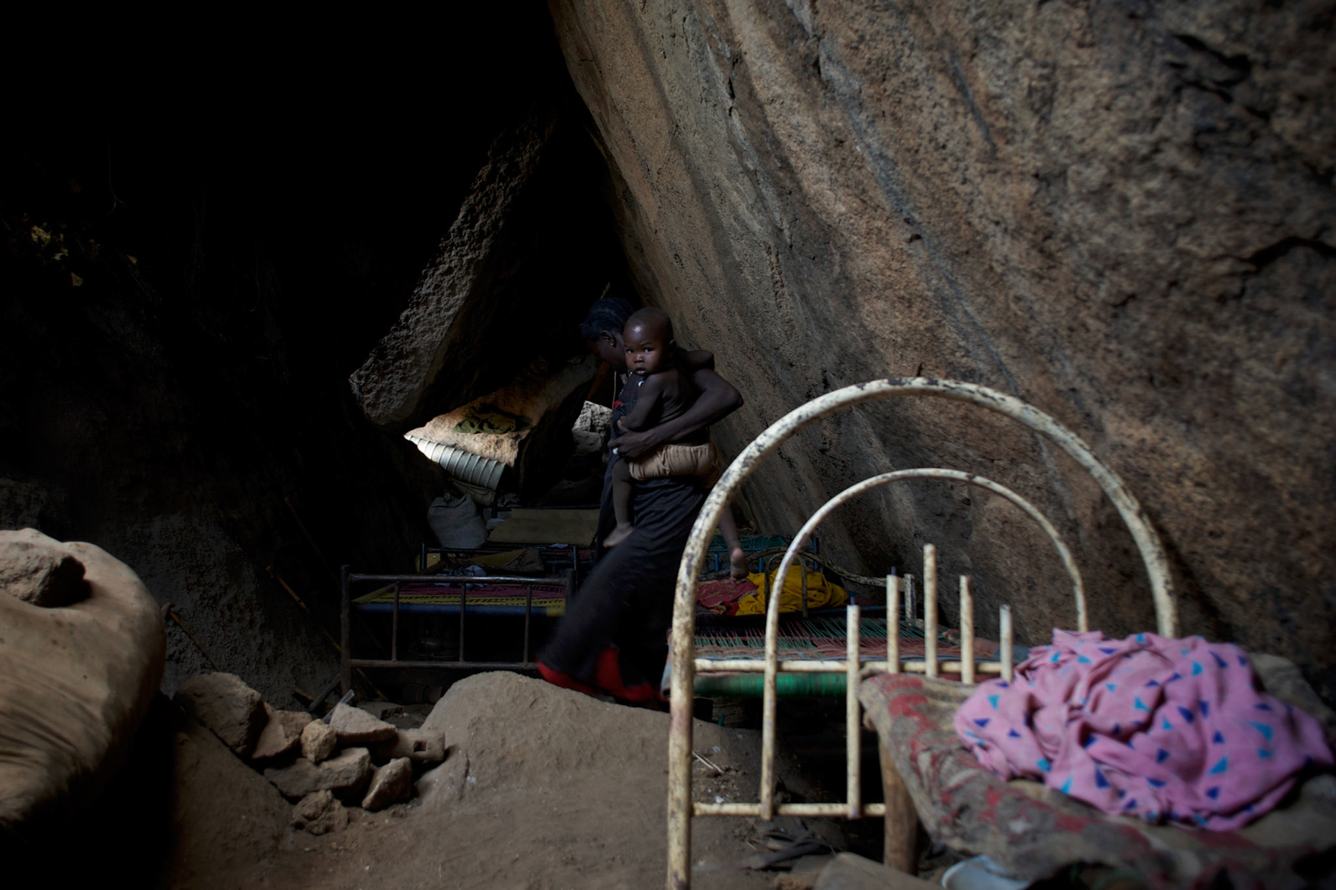 A Nuba family takes cover, from possible bombardments by Sudan's Army Forces airplane, in some caves near Buram village.