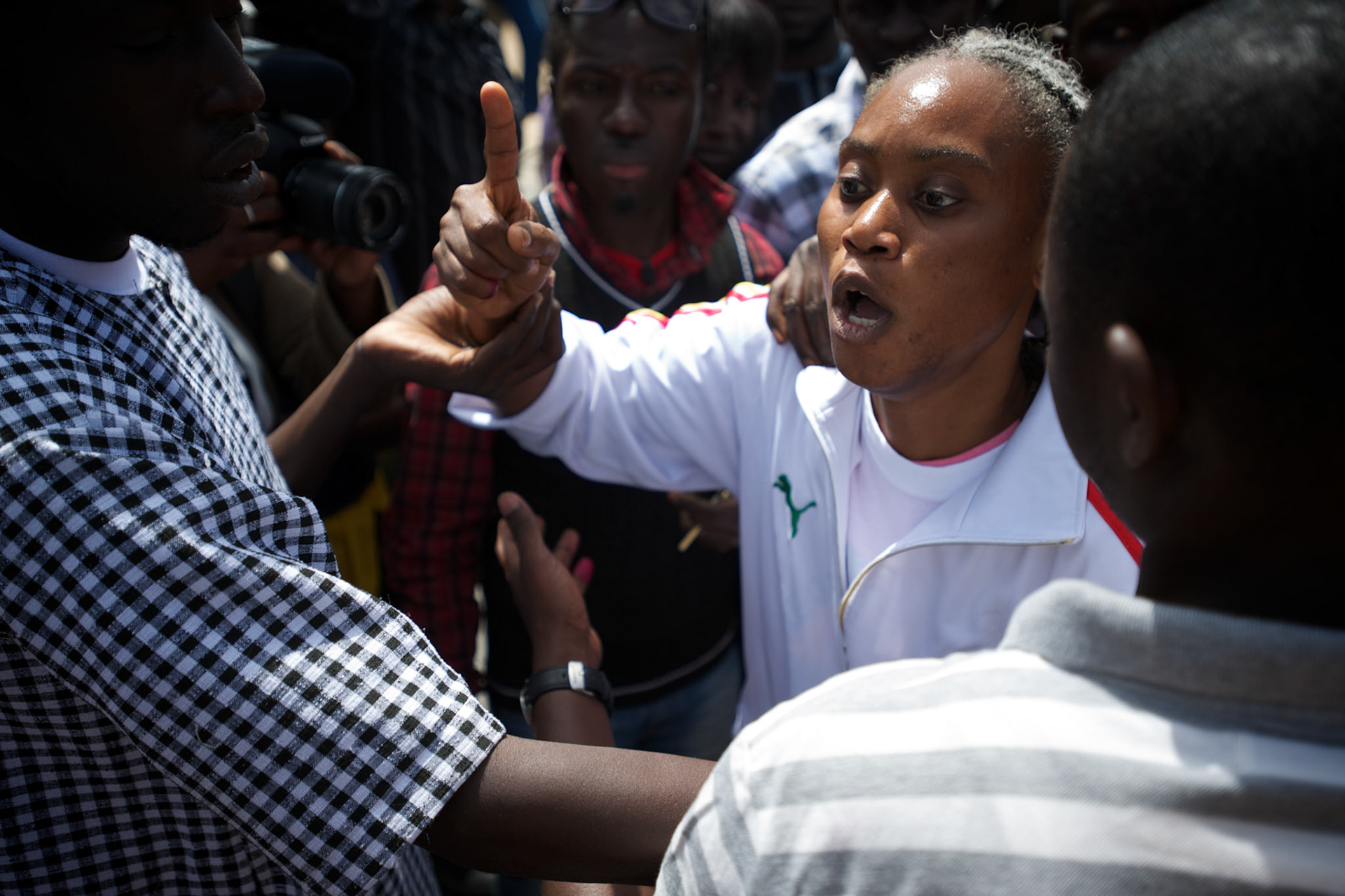 February 26, 2012 - Dakar, Senegal: Security men try to control a senegalese woman who was shouting insults against the president and candidate, Abdoulaye Wade, while voting at the Franco-Arab School in Point E area of Dakar. Hundreds of people queueing for voting insulted and heckled Wade, accusing the head of state of disrespect for the country's constitution when running for a third mandate. (Paulo Nunes dos Santos/Polaris)
