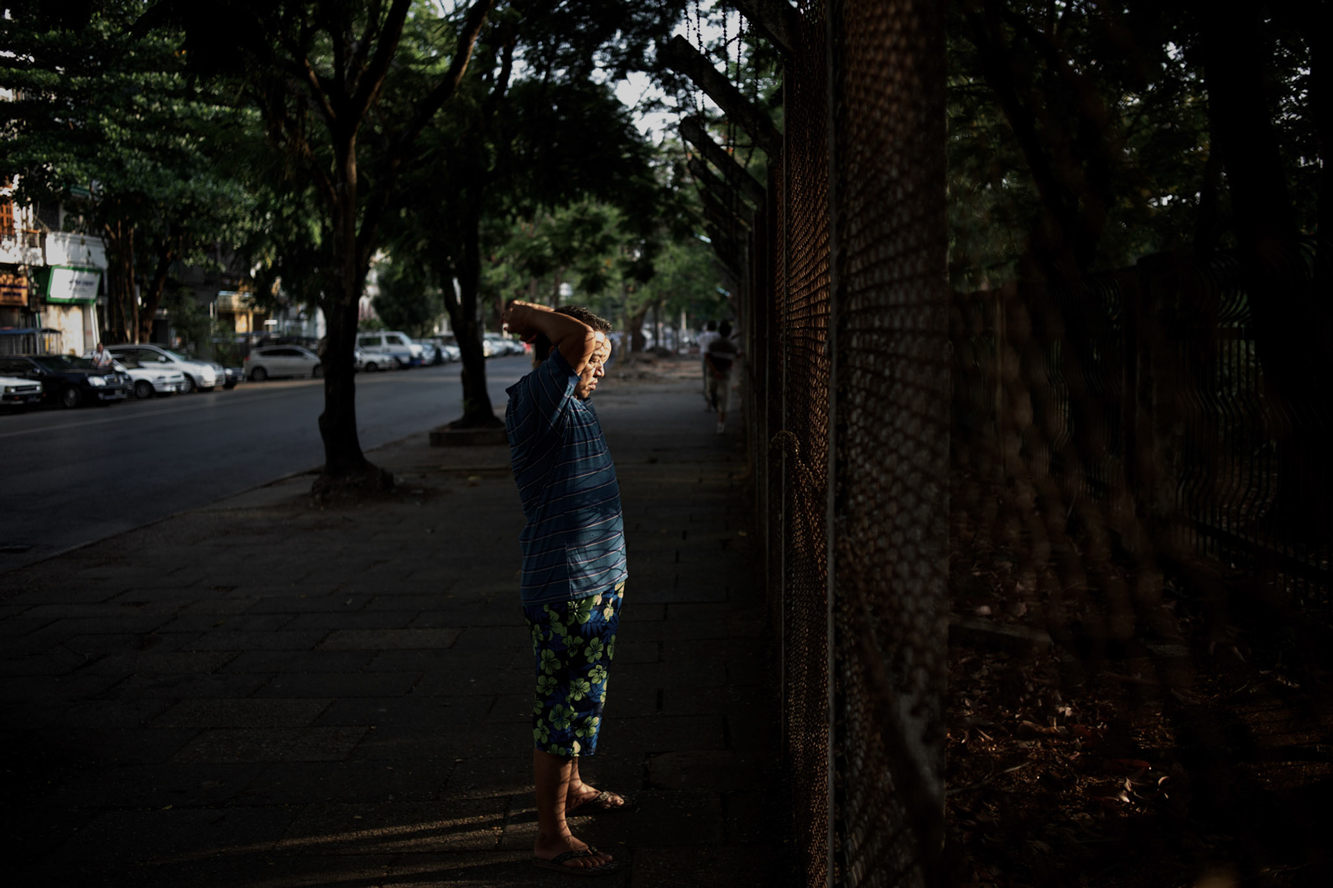 May 09, 2013 - Yangon, Myanmar: A local resident exercises in the early hours of the day, facing a fenced garden in central Yangon. CREDIT: Paulo Nunes dos Santos