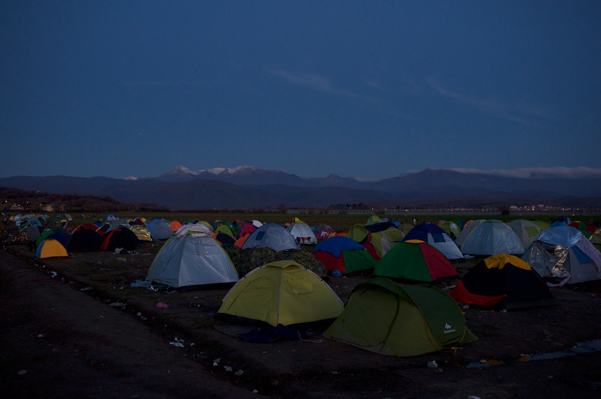 Migrants pass by tents set up near the border between Greece and Macedonia in Idomeni, Greece. Around 13,000 migrants and refugees, mostly from the Middle East and African nations, are believe to be stranded here awaiting a chance to proceed their journey towards Germany and other northern European countries.