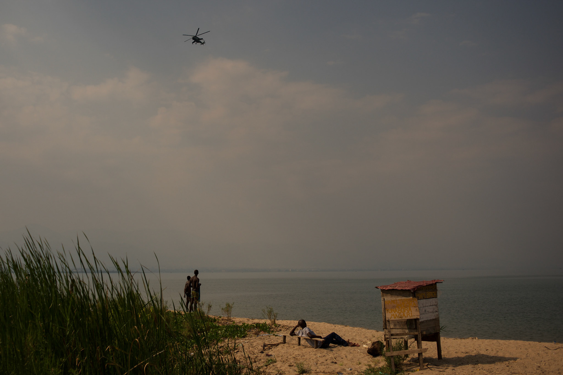 An army helicopter flies by as locals enjoy the beach at Lake Tanganyika in Bujumbura.