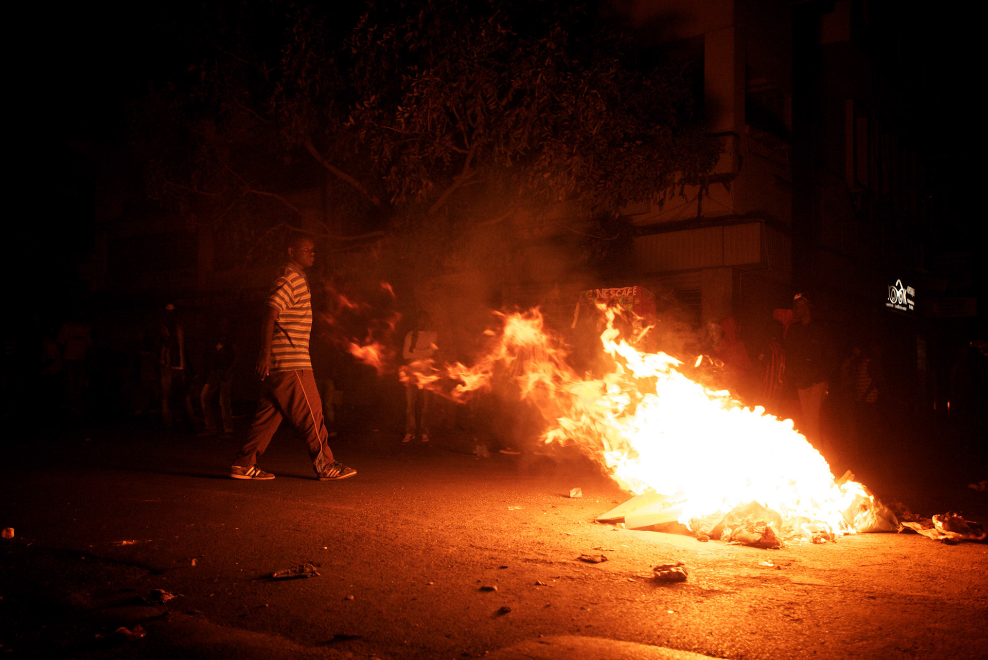 February 23, 2012 - Dakar, Senegal: A group of opposition supporters gather around a burning road block during a protest against the candidature of the current president Abdoulaye Wade for a anti-constitutional third candidature to as head of state. Tensions between police and opposition supporters have been high in the capital Dakar and other cities around the country, where some clashes have happen ahead of the presidential elections on the 26th of February. At least fourteen people have died in the past month. (Paulo Nunes dos Santos/Polaris)