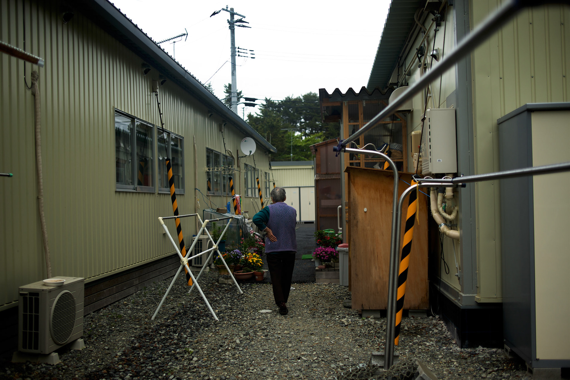 A displaced woman walks by prefabricated houses in Togura, used as temporary shelter for families who lost their homes during the devastating earthquake and tsunami that hit the east coast of Japan in 2011. On the third anniversary of the disaster, nearly 270,000 remain displaced.