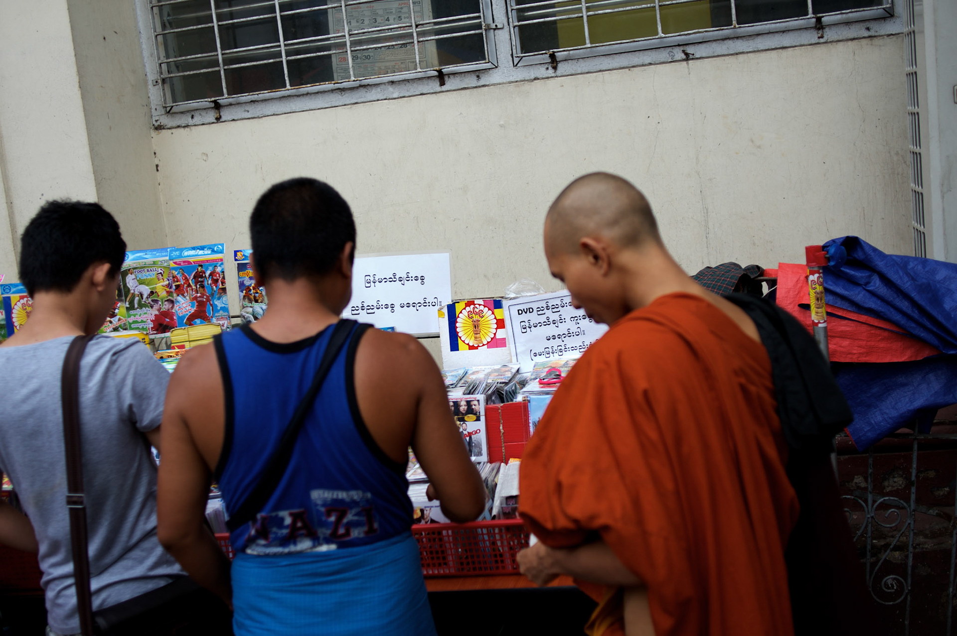 May 19, 2013 - Yangon, Myanmar: A buddhist monk buys goods at a CD stand marked with a sticker emblazoned with 969, the logo that has come to represent Myanmar's anti-Muslim movement. Taxis, buses, shop fronts and street stalls across the country display what some consider a symbol of Buddhistextremism that sees Burma's Muslim community as a threat to the country and its dominant religion. CREDIT: Paulo Nunes dos Santos