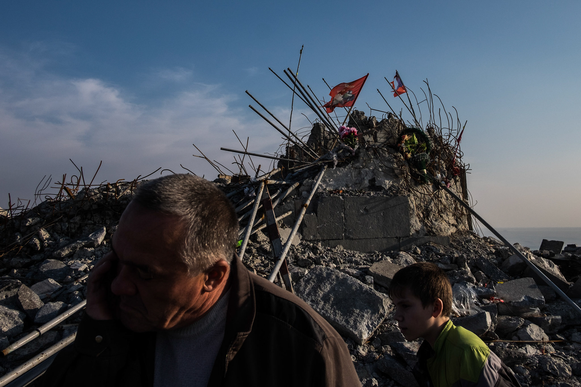 A father and son wander through the rubble of a WWII memorial complex near the Russian border, in Snizhne.