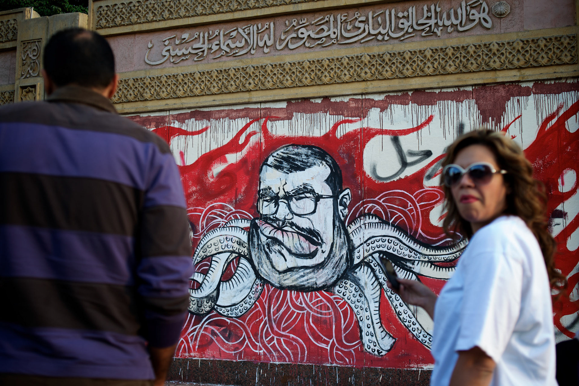 Bystanders look at a satirical graffiti of president Morsi, outside the presidential Palace in central Cairo.