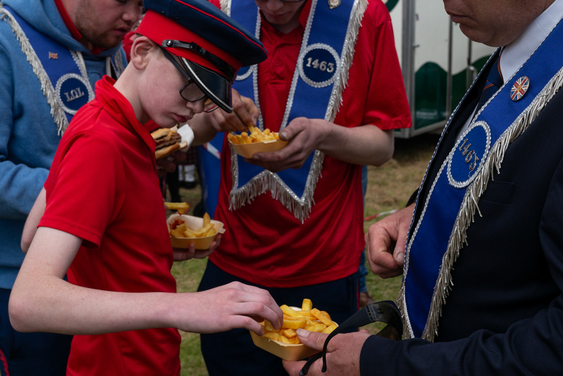 Members of a flute band eating chips after the annual Orange Order parade at Rossnowlagh Beach in Co. Donegal, Ireland, on July 06, 2024. Around 50 Orange lodges from Ireland and across Northern Ireland paraded down a country lane towards the seaside village of Rossnowlagh on Saturday, the only annual Orange Order parade in the Republic of Ireland. Thousands of people have attended the annual Orange Order parade which traditionally takes place on the Saturday before the main Twelfth demonstrations in Northern Ireland.