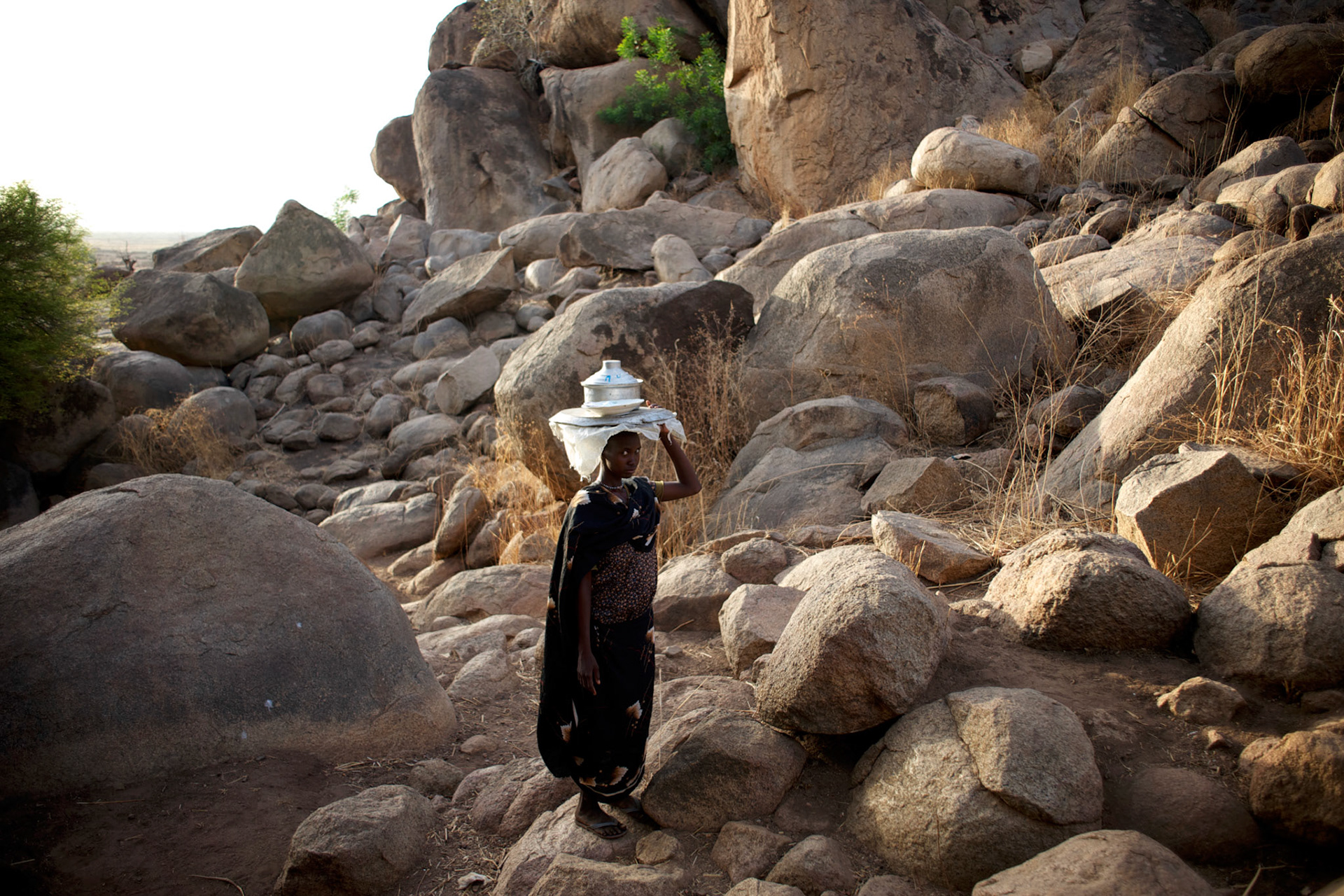 A Nuba woman passes by carrying a pot of food in the mountains outside Buram village in South Kordofan's Nuba Mountains.