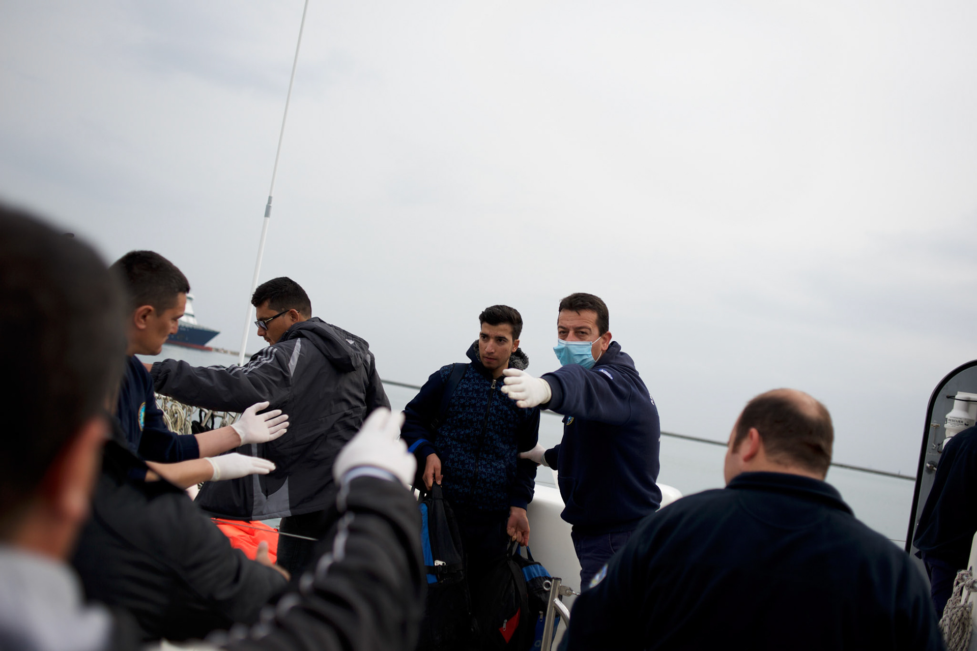 Migrants are seen been escorted out of a rescue boat arriving at Mytilene port in Lesbos island, Greece.
