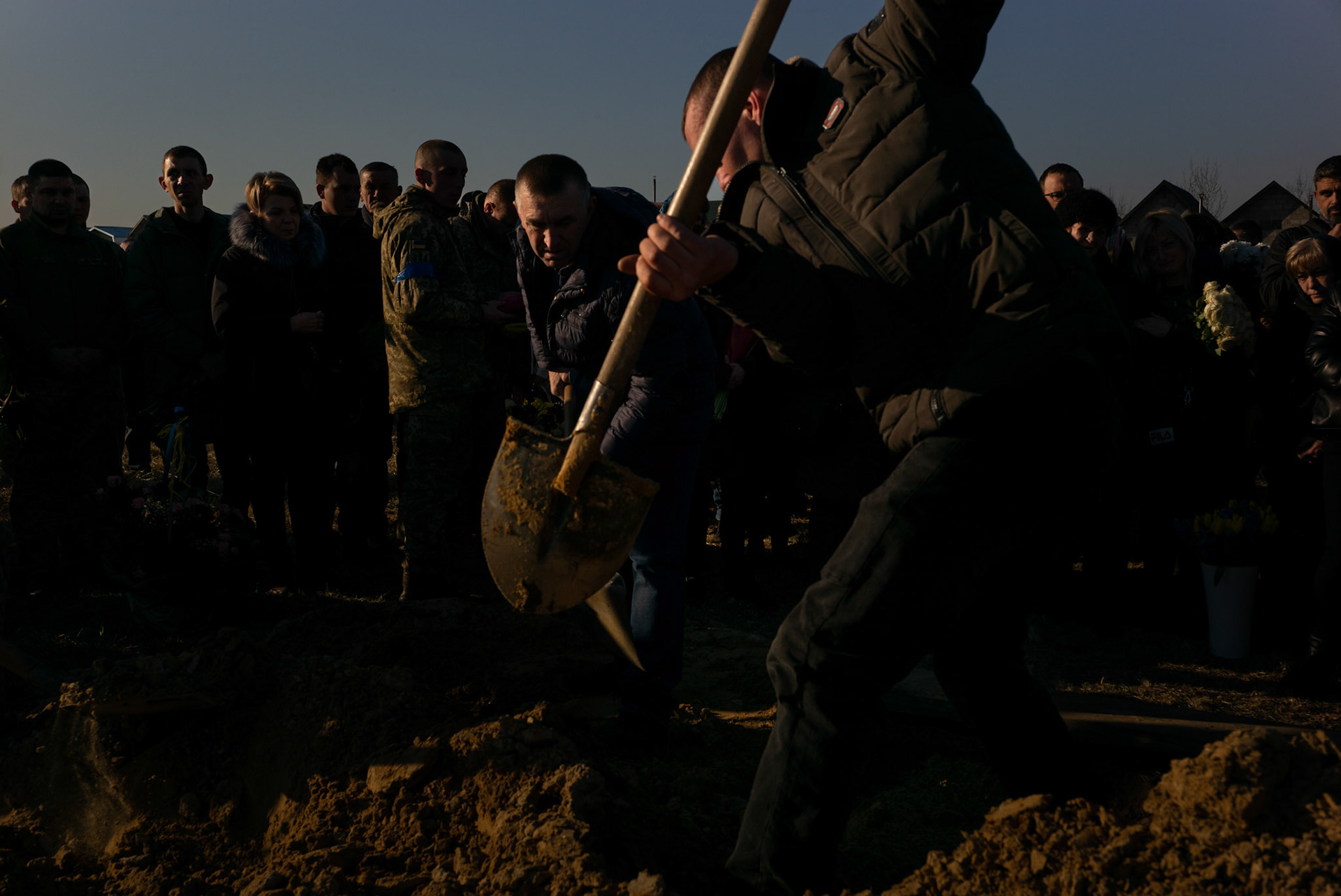 An Ukrainian man says goodbye to a Men throw soil over the coffin of Sergei Grigorovich, a Ukrainian soldier killed in combat and being buried in Starychi, a small village in the outskirts of Lviv.