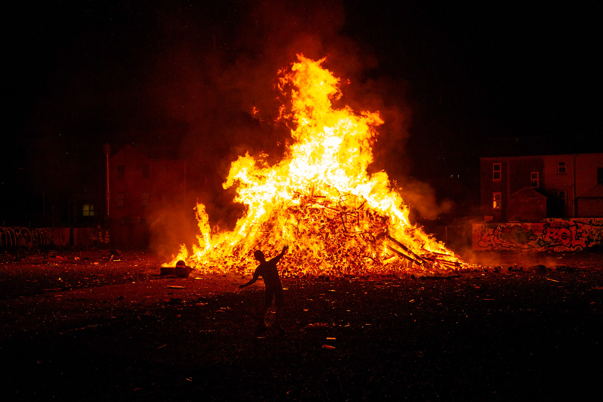 A youth throws empty canisters toward a burning bonfire during the Twelfth of July celebrations in Donegall Pass, a predominantly working-class loyalist community in inner-city Belfast, Northern Ireland, on July 12, 2021.
