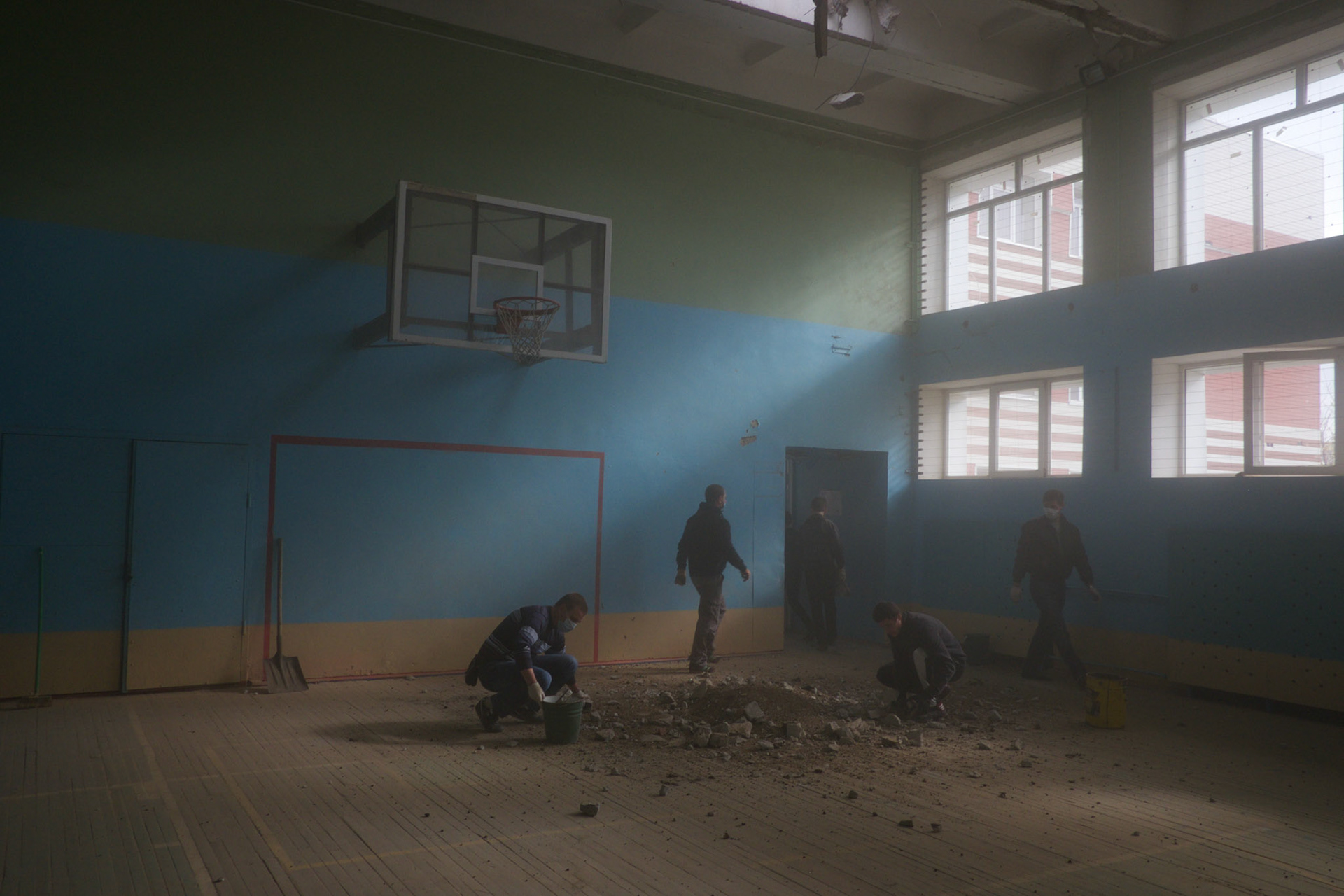 Local volunteers clean a school gymnasium damaged by shell-fire in Donetsk