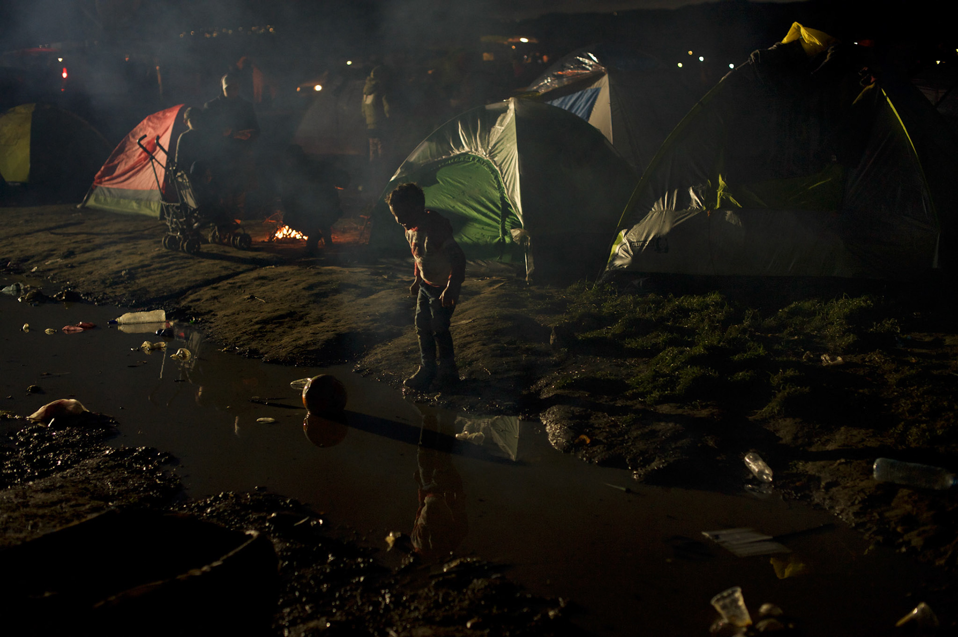 A migrant child plays in dirty water surrounding tents at the Greek-Macedonian border station of Idomeni, Greece. Around 13,000 migrants and refugees, mostly from the Middle East and African nations, are believe to be stranded here awaiting a chance to proceed their journey towards Germany and other northern European countries.