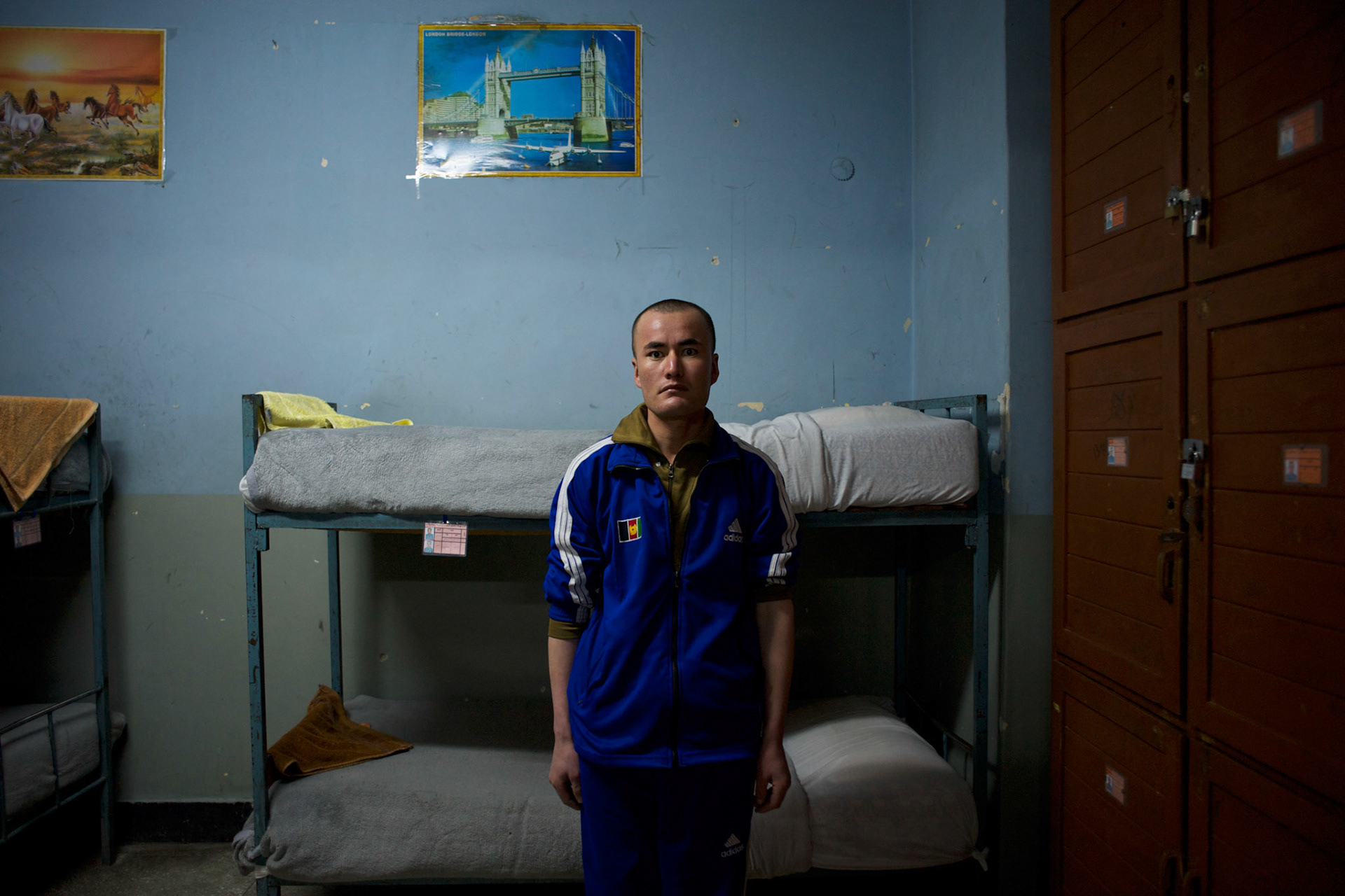 An Afghan National Police (ANP) cadet stands beside is bed at a dorm in the Afghan Nacional Police Academy in Kabul.