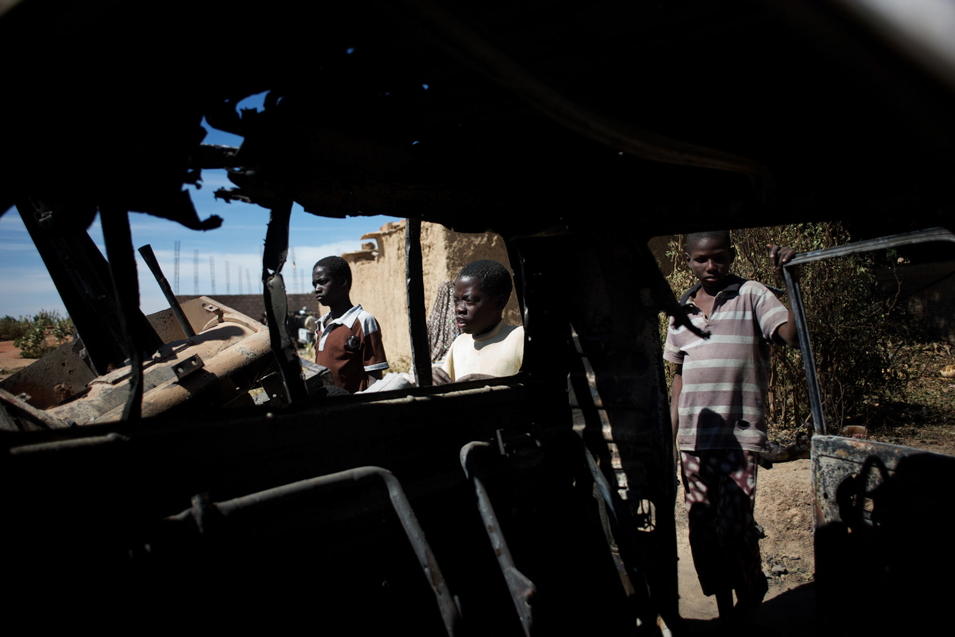 January 21, 2013 - Diabaly, Mali: Local children scavenge destroyed islamic militants' armoured vehicles in central Diabaly, a day after Mali government troops regain control of the city. Diabaly was under islamist militants control since the 14th of January.Several insurgent groups have been fighting a campaign against the Malian government for independence or greater autonomy for northern Mali, an area known as Azawad. The National Movement for the Liberation of Azawad (MNLA), an organisation fighting to make Azawad an independent homeland for the Tuareg people, had taken control of the region by April 2012.The Malian government pledge to the French army to help the national troops to stop the rebellion advance towards the capital Bamako. The french troops started aerial attacks on rebel positions in the centre of the country and deployed several hundred special forces men to counter attack the advance on the ground. (Paulo Nunes dos Santos)