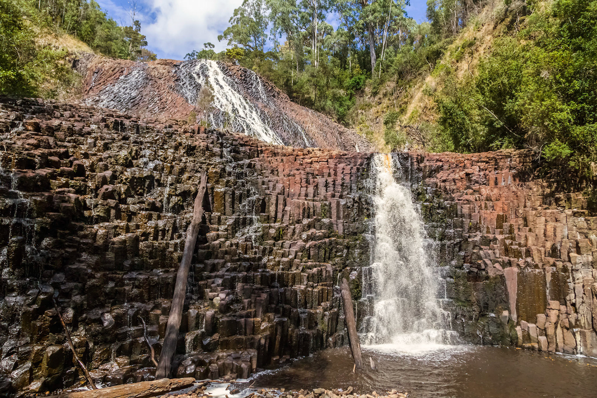 Dip Falls. Two-tiered waterfall with the water flowing over cubic-basalt columns of volcanic origin. In the Dip River Forest Reserve.