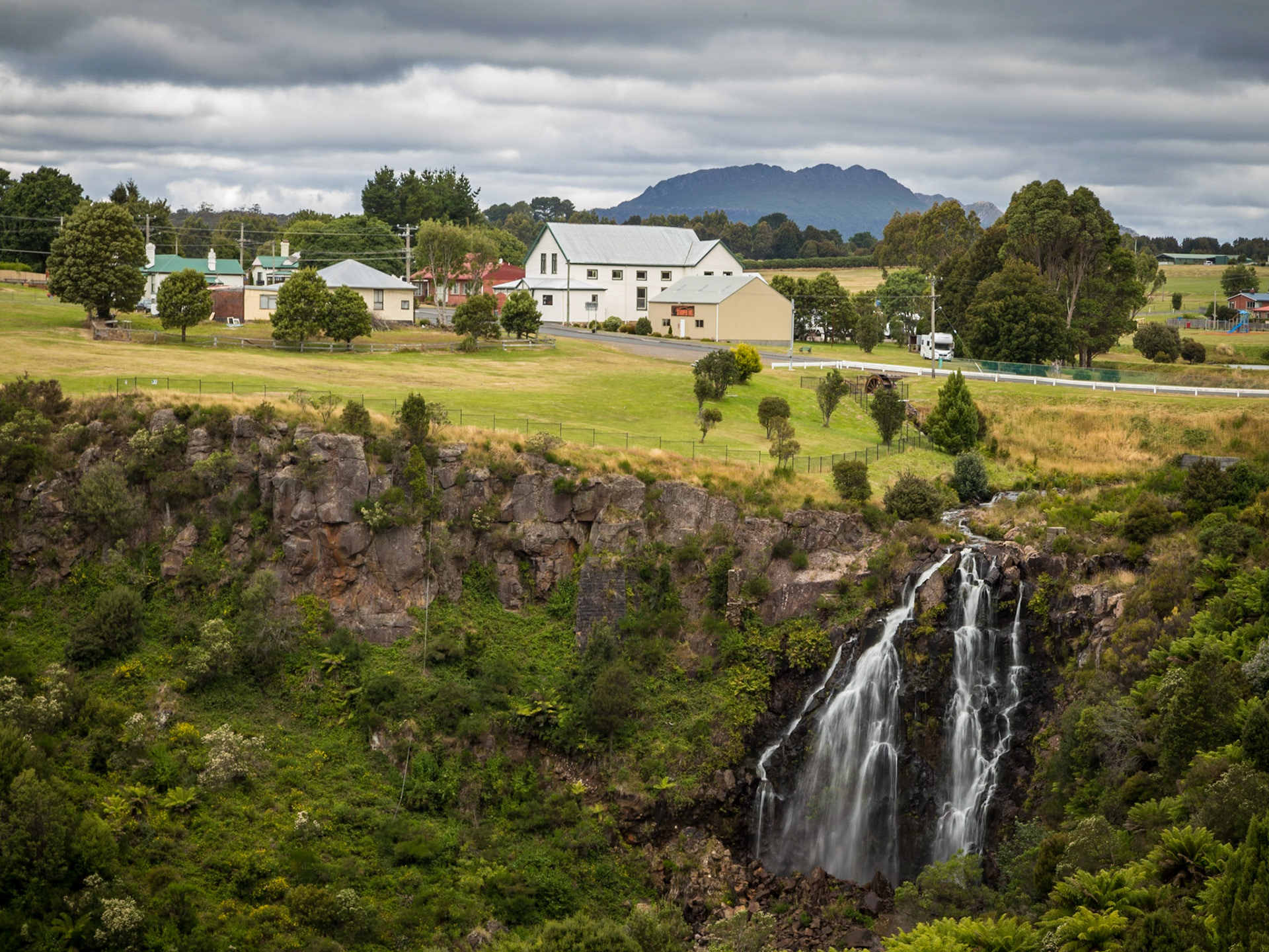 Waratah Waterfall, seen from Main Street. View across to the Athanaeum Hall and Mount Pearce in the background
