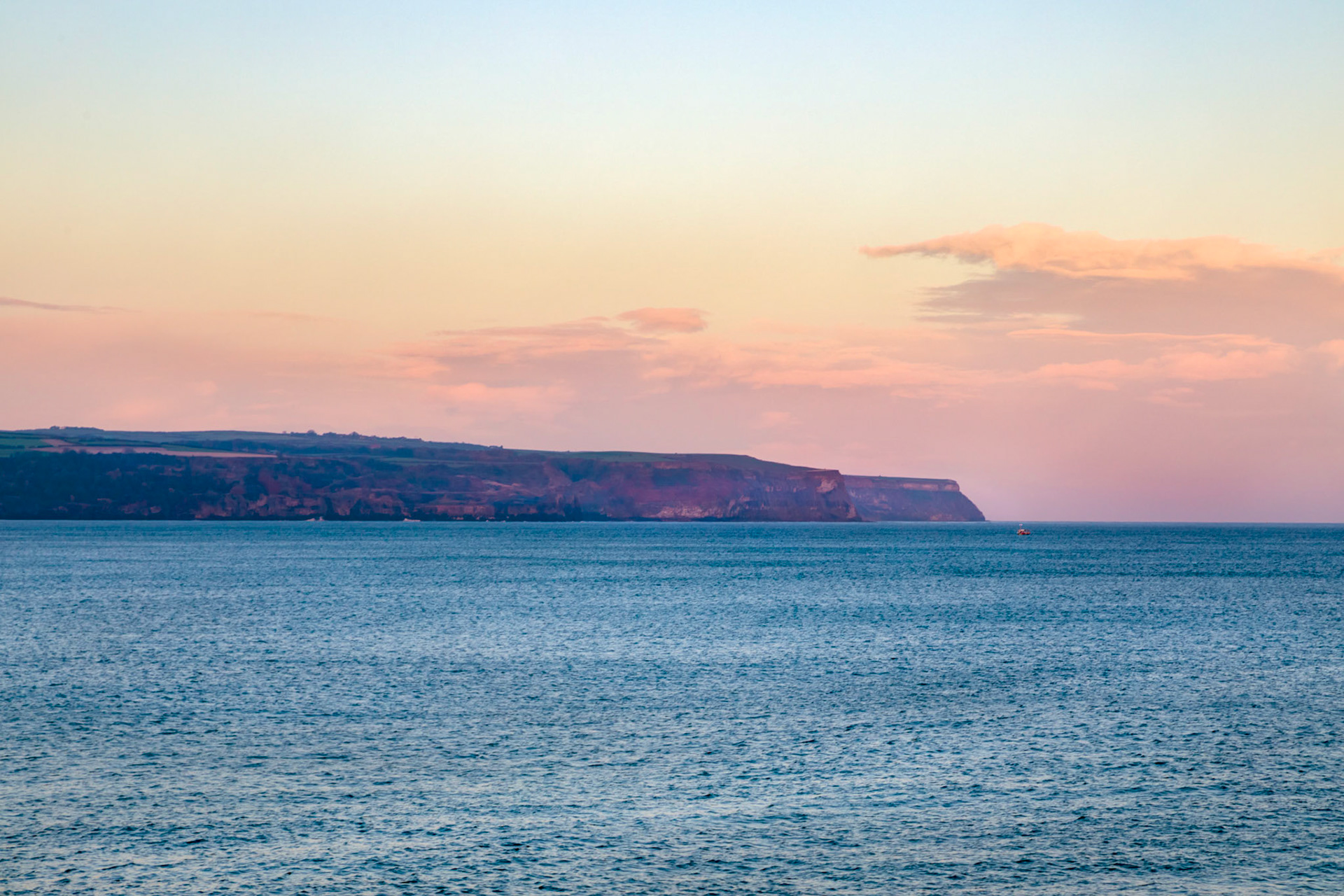 At sunrise,  the view up the coast to the north west from the Whitby harbour seawall
