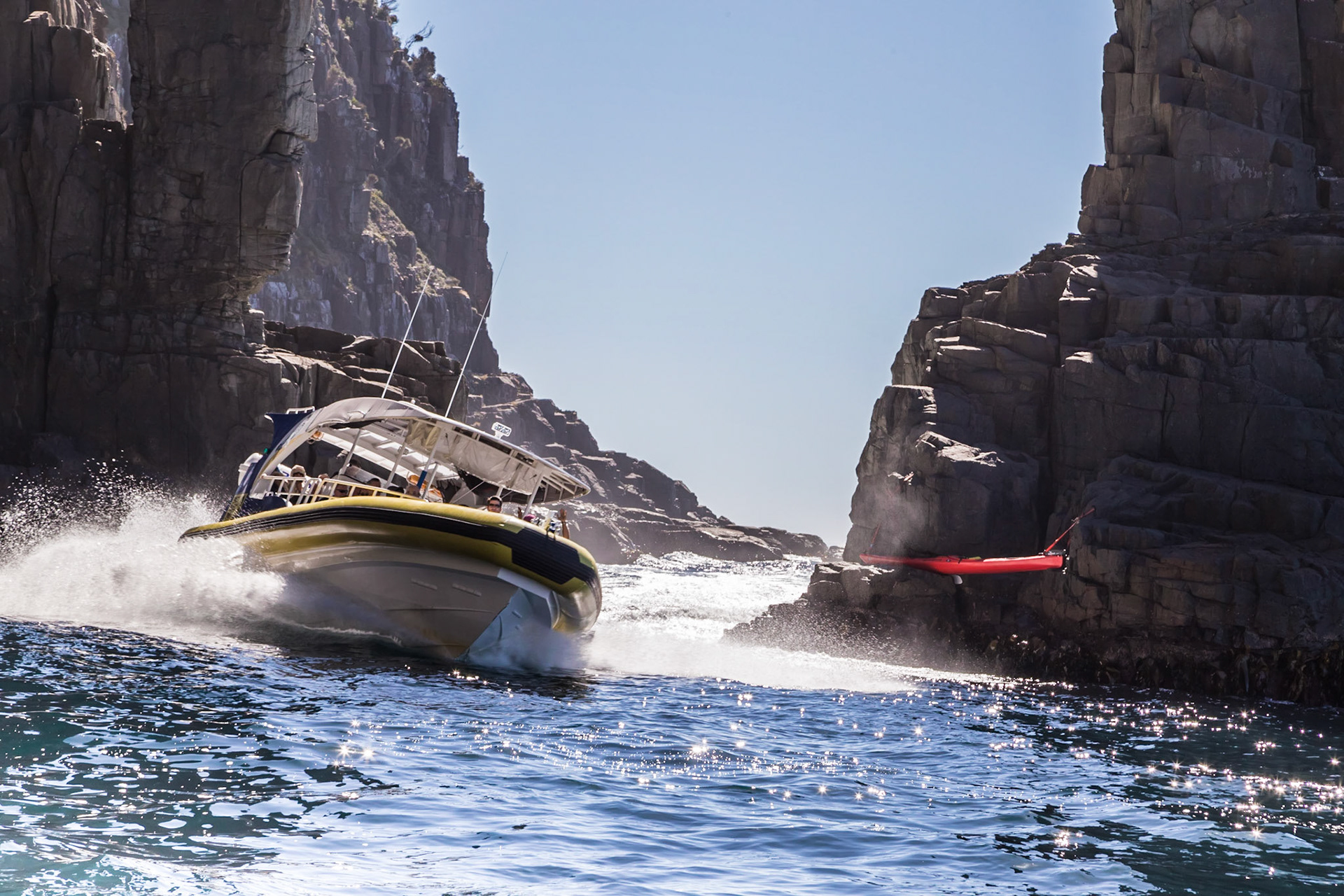 Speeding through the narrow gap between the cliff and 'The Monument' gap. Pennicott Bruny Island Cruises.