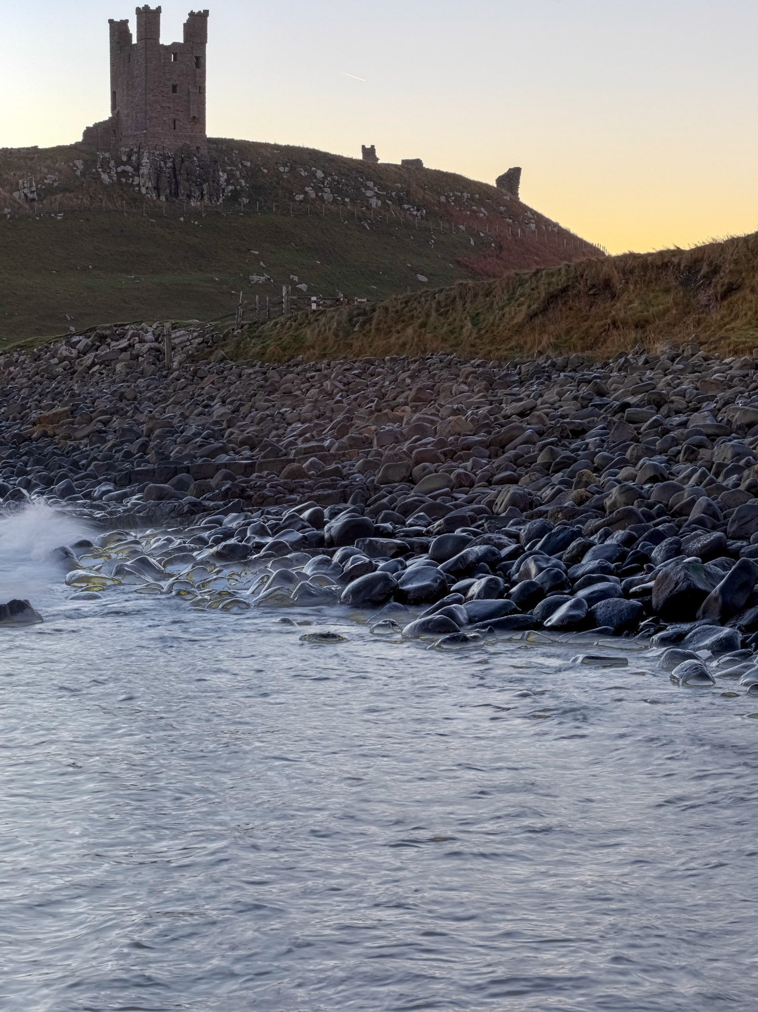 Dunstanburgh Castle in silhouette at sunrise