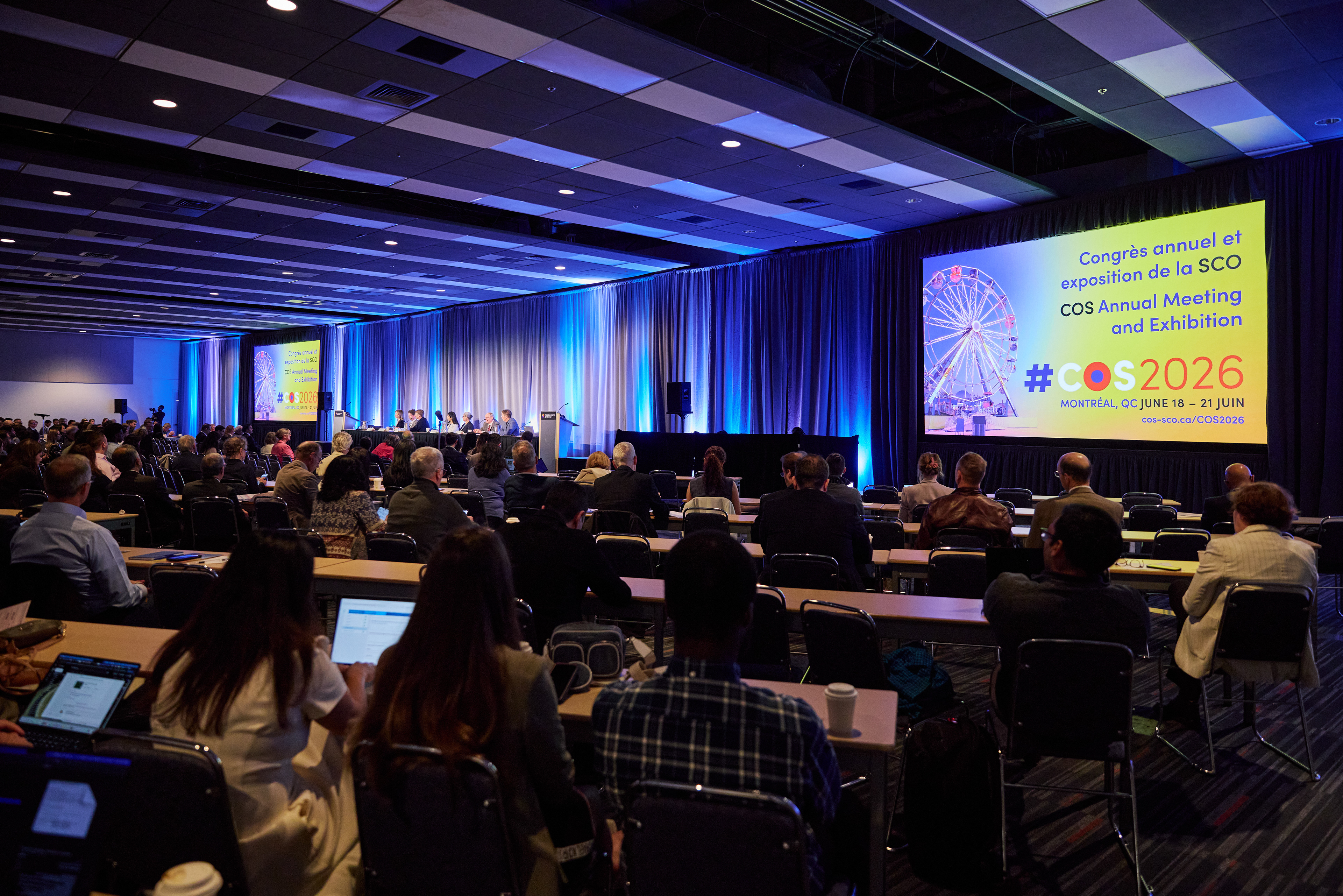 A wide photograph of a packed lecture hall, screens flanking both sides of the stage reading "Congrès annuel et exposition de la SCO COS Annual Meeting & Exhibition #COS2026 Montréal, CQ June 18 - 21 Juin cos-sco.ca/COS2026"