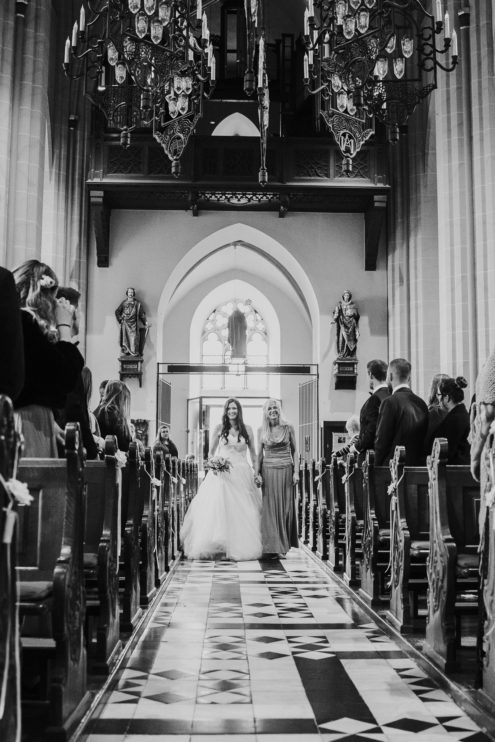 Braut schreitet mit Brautmutter zum Altar