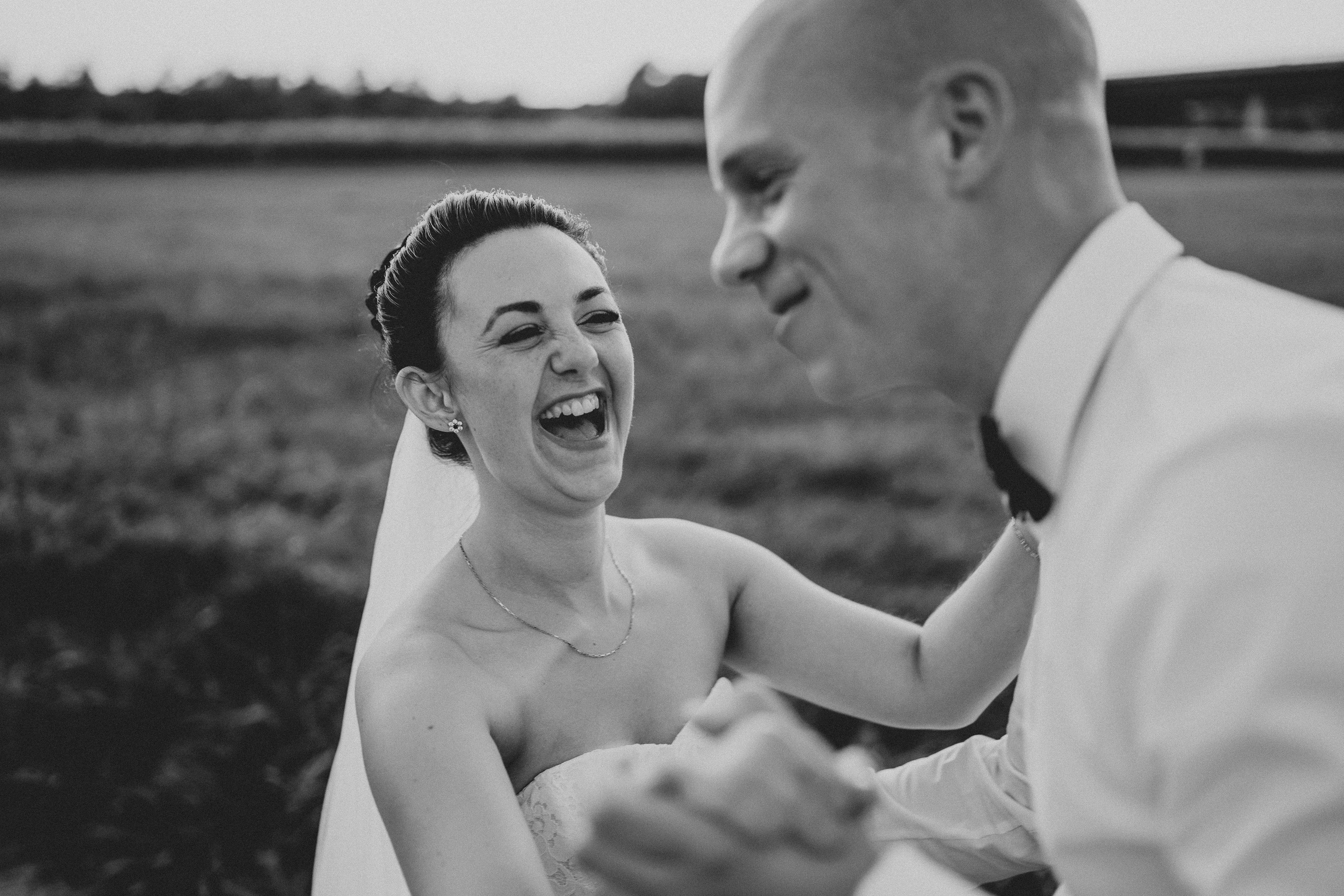 Braut Lacht und Tanst  mit ihrem Ehemann. Paarshooting am Rhein