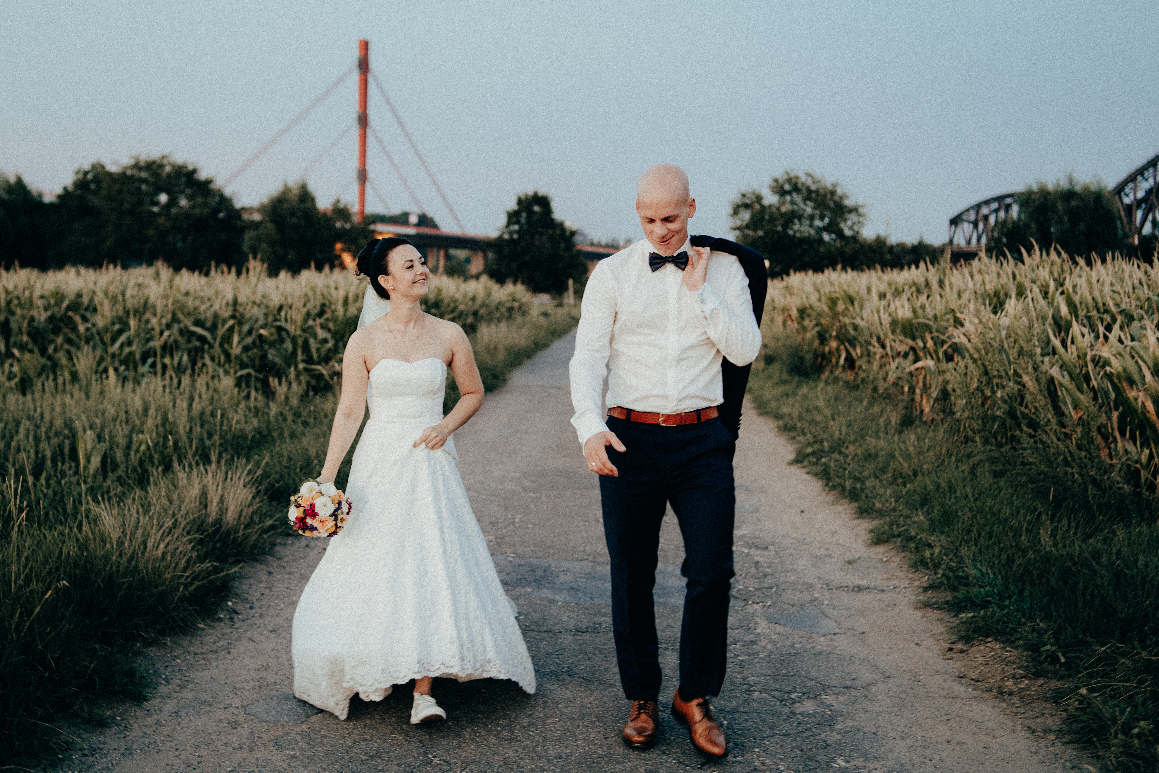 Braut und Bräutigam laufen auf einem Weg. Paarshooting am Rhein