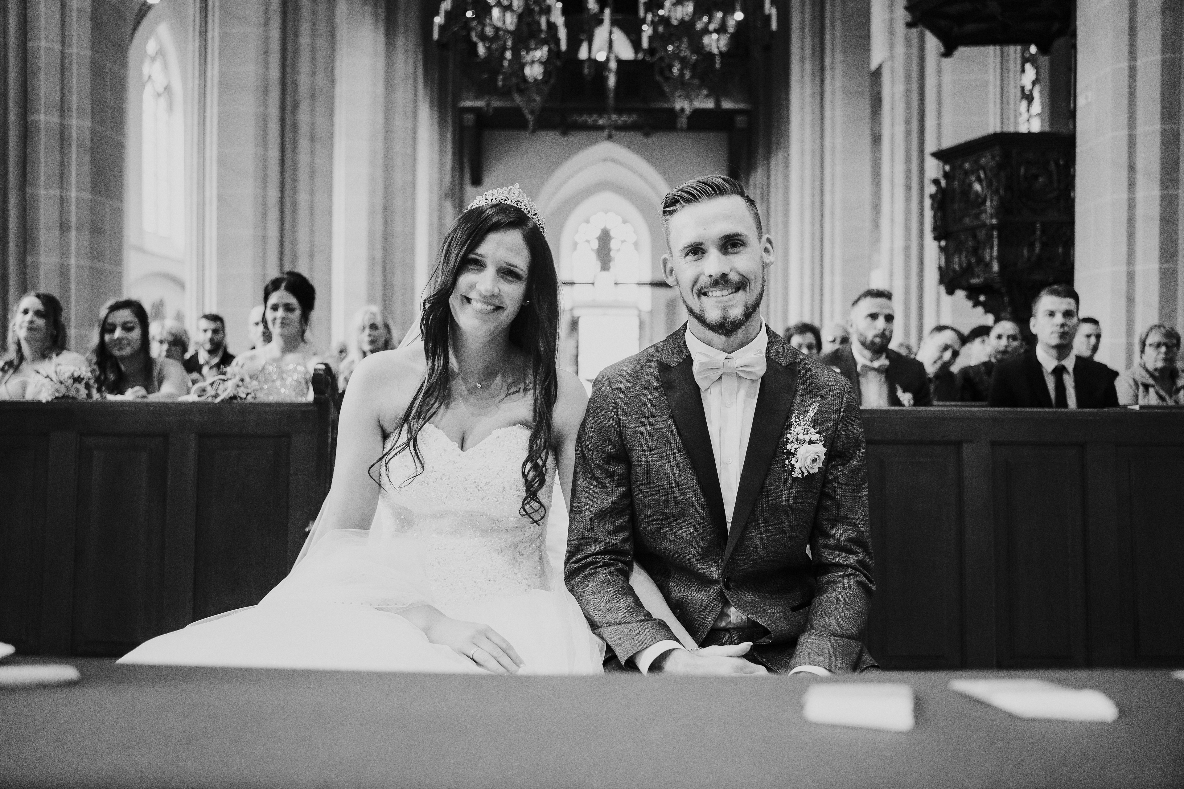 Brautpaar vor der Gemeinde sitzend. Lachend in die Kamera