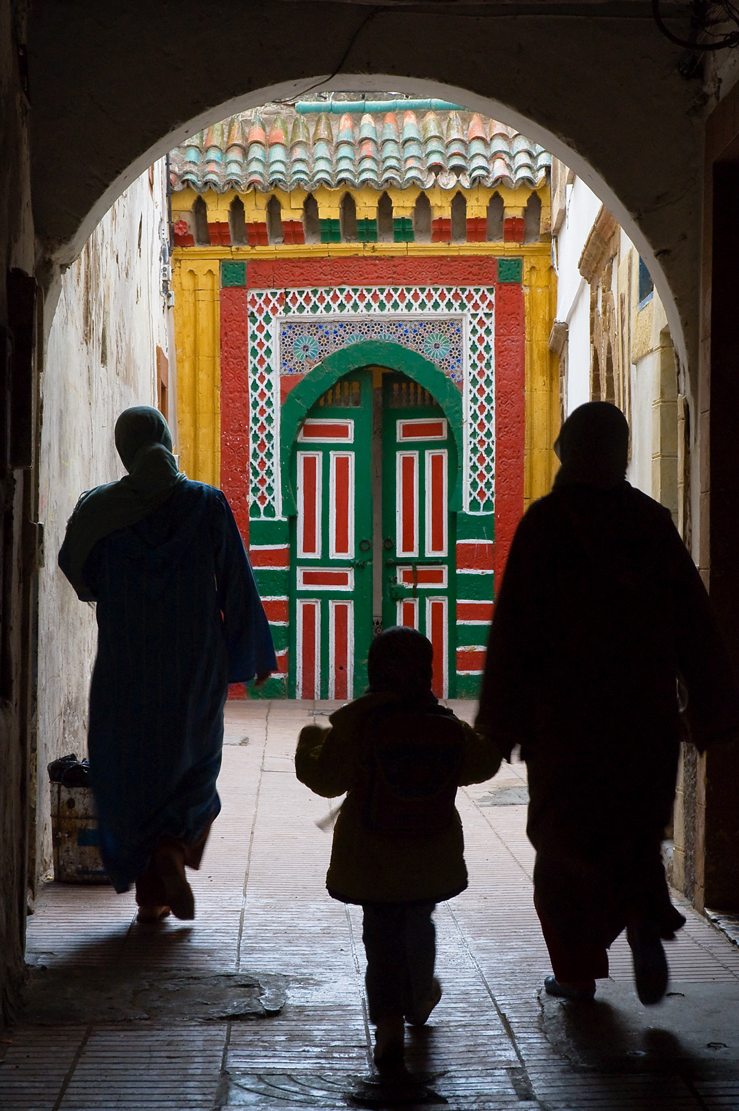 Two women and a child walking towards Essaouira's Dar Dmana.