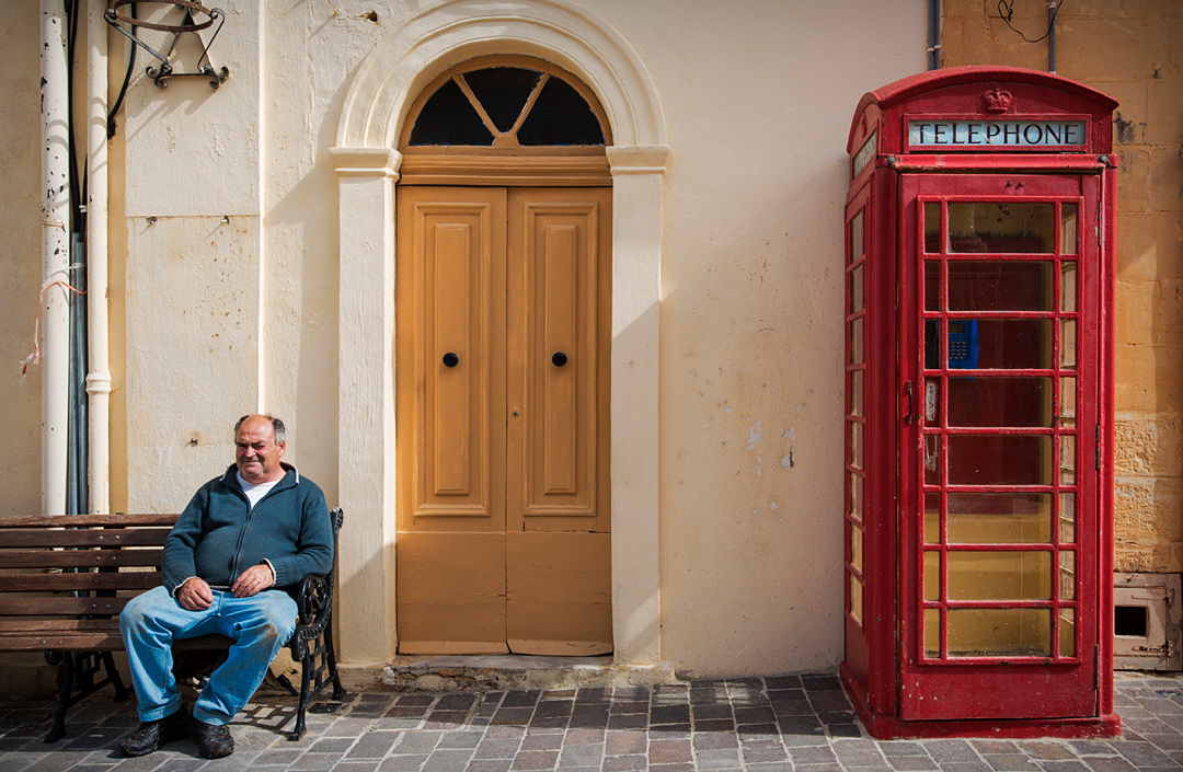 A man and a typical english red telephone box in San Lawrenz, a village of Gozo. 