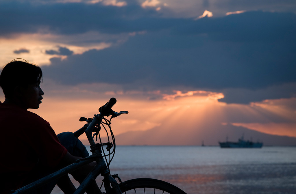Manila.  A boy watching the sunset in Manila´s bay from Roxas Bulevard. 