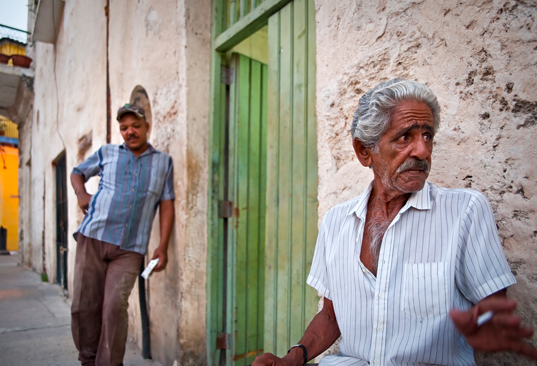 People in Habana Vieja. The youth listen sceptically elder's histories about times before the Revolution.