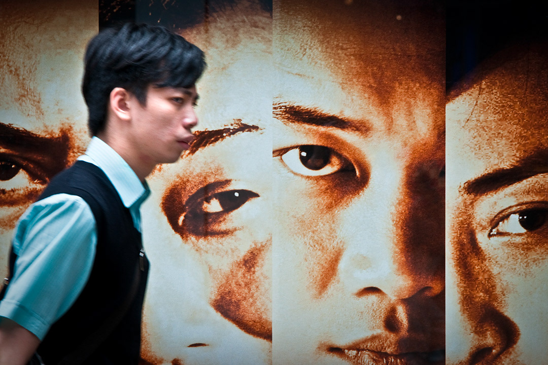  A man walking in front of a advertisement in Hong Kong. 