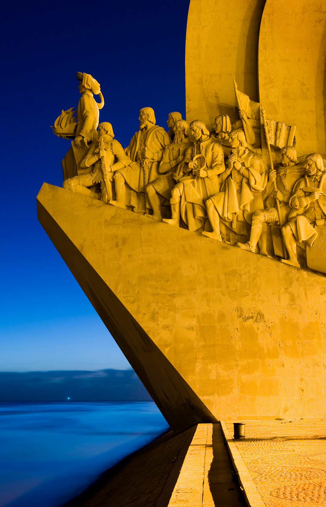 Pradao dos Descobrimentos. Monument of the Discoveries dedicated to Portuguese sea explorers and the 25 of April bridge at dusk. 