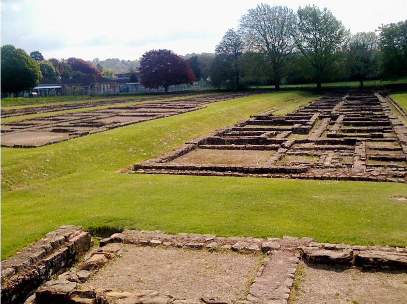 Stone outline of Roman buildings on a field with trees