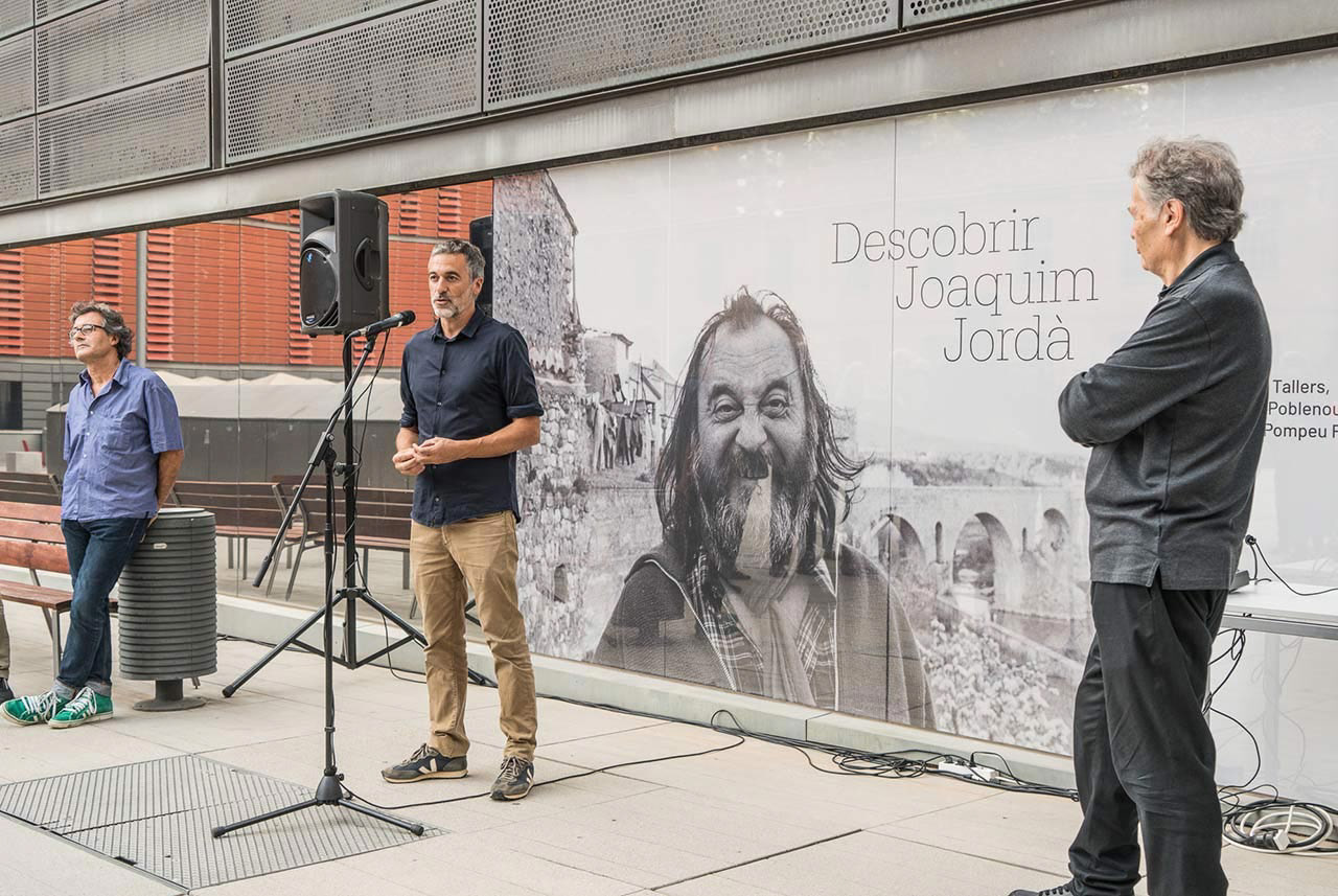 Toni Montes, standing in front of the exhibition banner, giving an introductory speech for the opening day.
