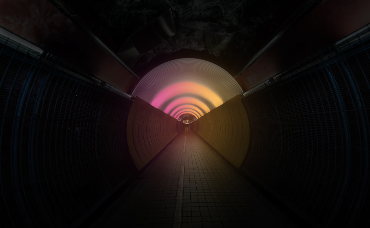 The immersive light installation showing a warm sunrise aura with pink lights on the left side of the tunnel, orange lights on the right side of the tunnel thus creating a blend of light in the middle.