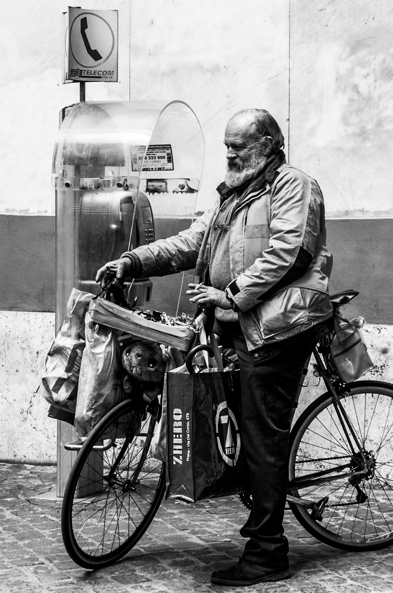 Detached: With all his worldly possessions hanging from his bike, he passes a phone. But there is no-one in his life to connect with, except the stuffed bear he carries on his bike.
