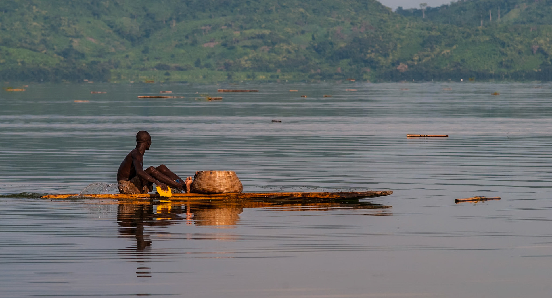 A Padua fisherman paddles across the smooth waters of Lake Bosumtwi. The only natural lake in Ghana, it is situated within an ancient impact crater approximately 10.5 km across. There is a traditional taboo against touching the water with iron and modern boats are frowned upon. The padua, a wooden plank requiring considerable skill to operate, is the only acceptable method of crossing the lake.