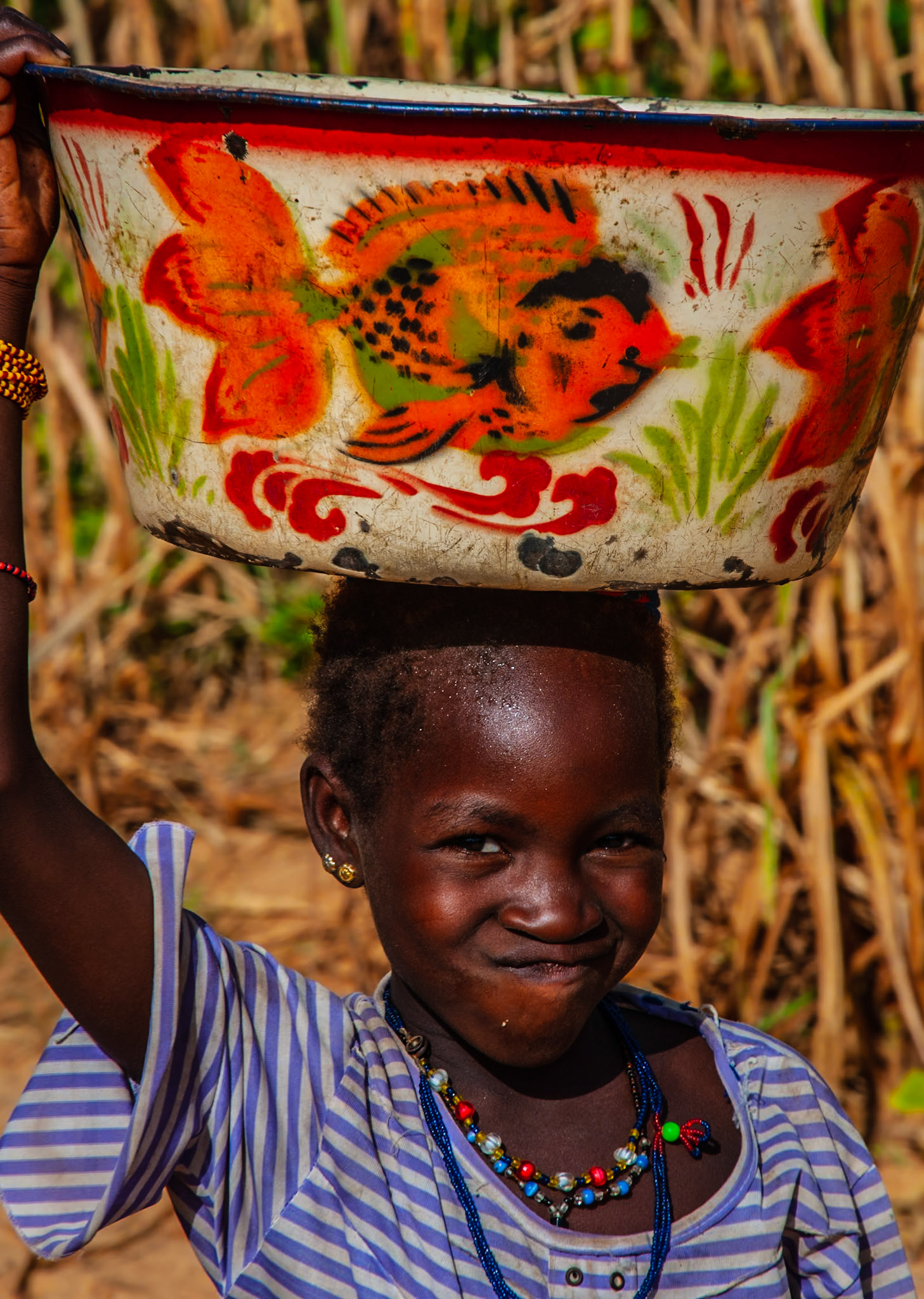 All children across the world are the same - a young Cameroonian girl pulls a face while doing her chores, carrying cassava for her mother to prepare. Cassava is a staple vegetable in the African diet; however, it is poisonous unless properly prepared.