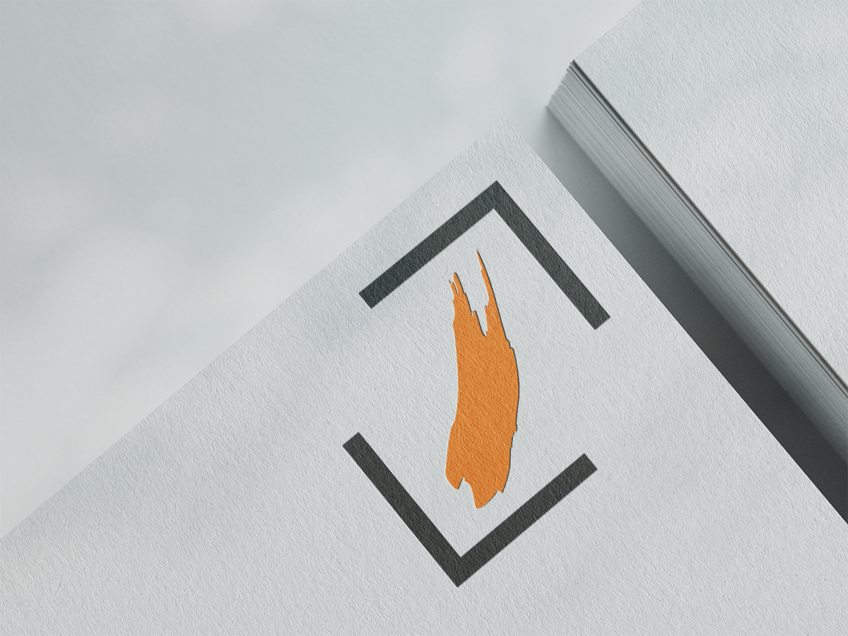 Nahaufnahme eines Papierstapels worauf ein Logo mit einem orangefarbenen Pinselstrich, das von einem schwarzen Rechteck umrahmt ist, zu sehen ist