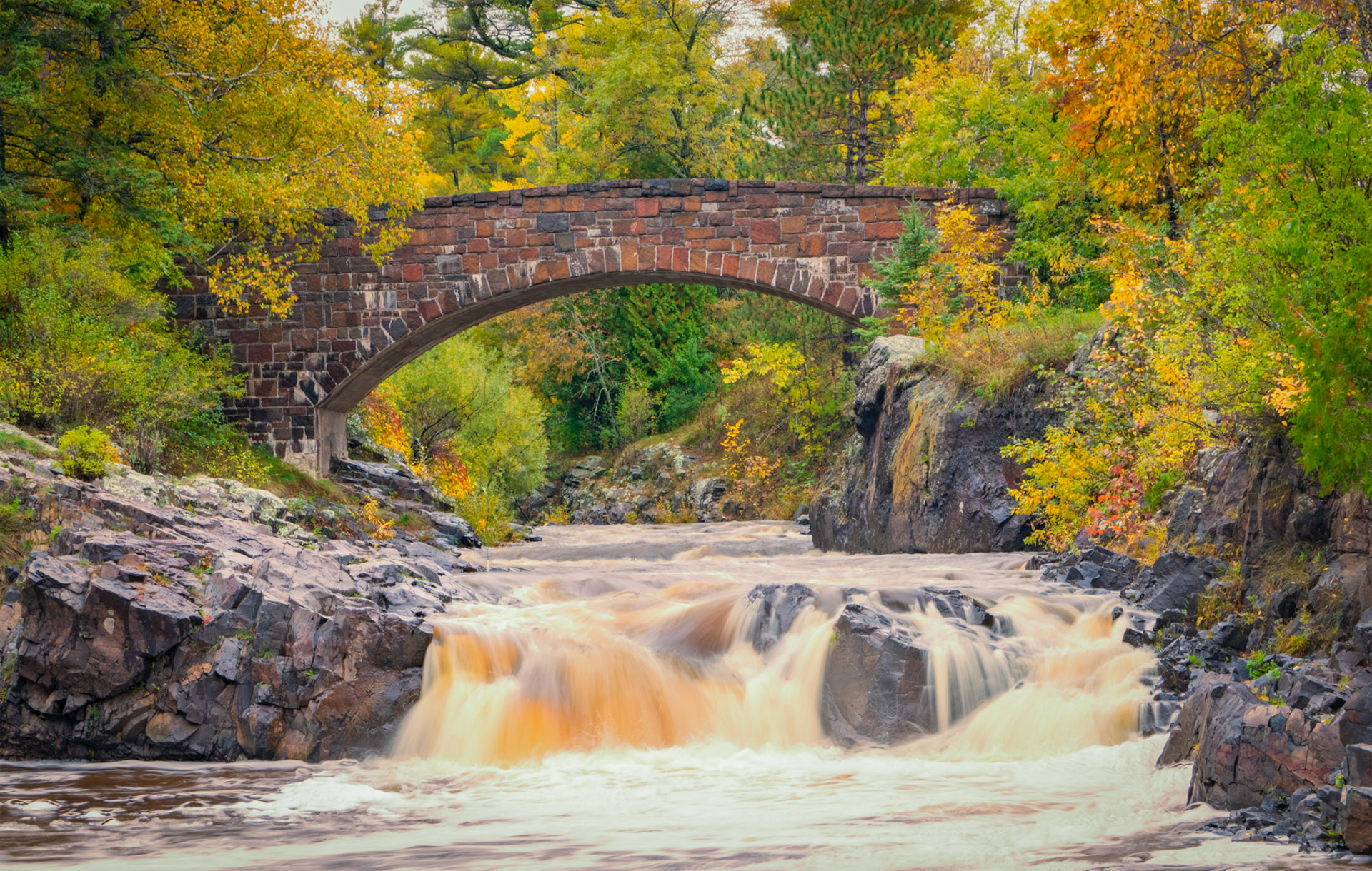 October 9 - Bridge Over Troubled Waters - The Lester Park Bridge, built in 1928, has stood firm for nearly 75 years. With constant October rainfall in the area, the river has swollen, and the fall foliage makes for a beautiful backdrop for pictures.Like the stone bridge in the picture, God is a steady foundation in times of trouble and makes a way across troubled times."When you pass through the waters, I will be with you; and through the rivers, they shall not overwhelm you; when you walk through fire you shall not be burned, and the flame shall not consume you." - Isaiah 43:2