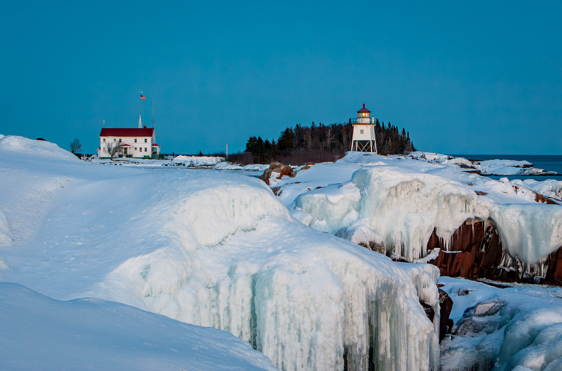 February 6 — Ice CapsGrand Marais Harbor is a gem of the Northland, and especially in winter, it shines with crisp, icy scenes that take your breath away — even if the cold doesn’t. Here, icicles cling to the bedrock like frosting on a cake.February’s chill still hangs in the air, but daylight is stretching longer, and the sun rises higher in the sky, creating the perfect conditions for these frozen sculptures.This time of year carries a quiet hope — the promise of warmer days and color returning to the landscape. Even when you can’t see it yet, there’s a deep sense that things are looking up after the dark days of winter.“See, I am doing a new thing! Now it springs up; do you not perceive it? I am making a way in the wilderness and streams in the wasteland.” — Isaiah 43:19It is a good reminder that even when we don’t see God at work, if we lift our eyes in faith, we will find thankfulness for today and strength for tomorrow from the God of Promises.