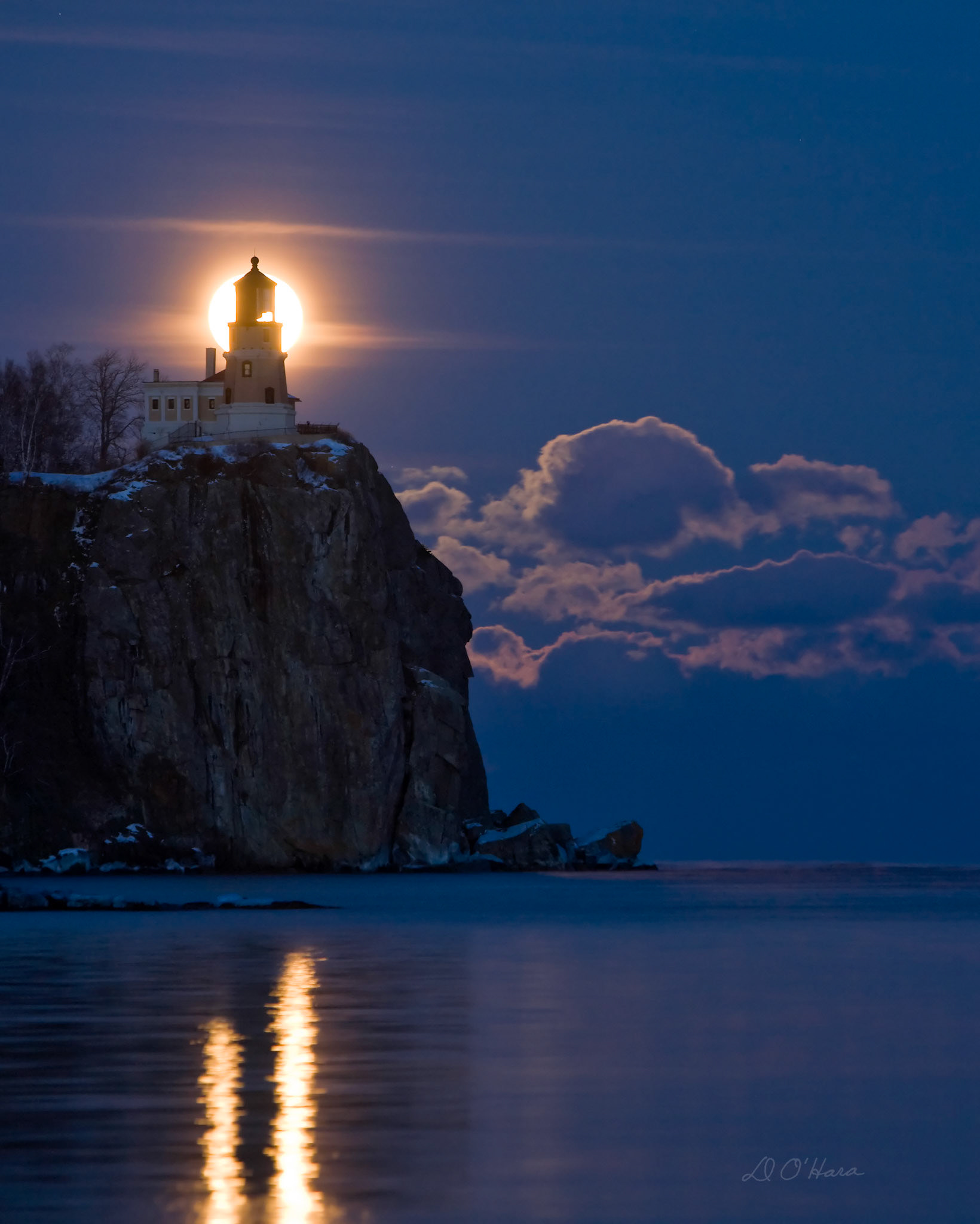 On and off snow showers throughout the day made it questionable whether or not it would be possible to photograph Split Rock Lighthouse on this January evening. The January Full moon is the only night of the year when it’s possible to photograph the lighthouse and moon together from this particular angle.  I decided to take my chances and make the one-hour drive to the lighthouse and hope that the sky would clear and the moon would be visible.As it turned out, it was a beautiful evening on the ice-covered shores of Lake Superior, and the +5F temperature made it quit pleasant. I was able to enjoy a nice chat with a few other photographers who had already arrived and we all scratched our heads, trying to figure out where exactly the moon would come up.It wasn't long before the first glow of the moon popped through the scattered clouds, and everyone adjusted their tripods and lenses to capture a most incredible and relatively rare sight.I fiddled with my camera controls making adjustments for the changing light, and took a dozen pictures while the moon transited through the horizon. It was an unforgettable sight, and one I hope you enjoy.On the drive home, I though about the history of this wonderful lighthouse which has stood sentinel atop the 160 foot cliff for nearly 100 years. I though about the old light keepers who hauled supplies from the lake up the steep cliff and faithfully tended to the beacon, in good weather and bad. They must have watched the January full moon rise with the same awe that we do today.Split Rock has withstood the elements for so long because of its solid rock foundation. Rocks have always represented the strength and power of our creator God, and that is why his creation reveals his attributes in such magnificent ways.The LORD is my rock, my fortress, and my savior; my God is my rock, in whom I find protection. He is my shield, the power that saves me, and my place of safety. Psa 18:2