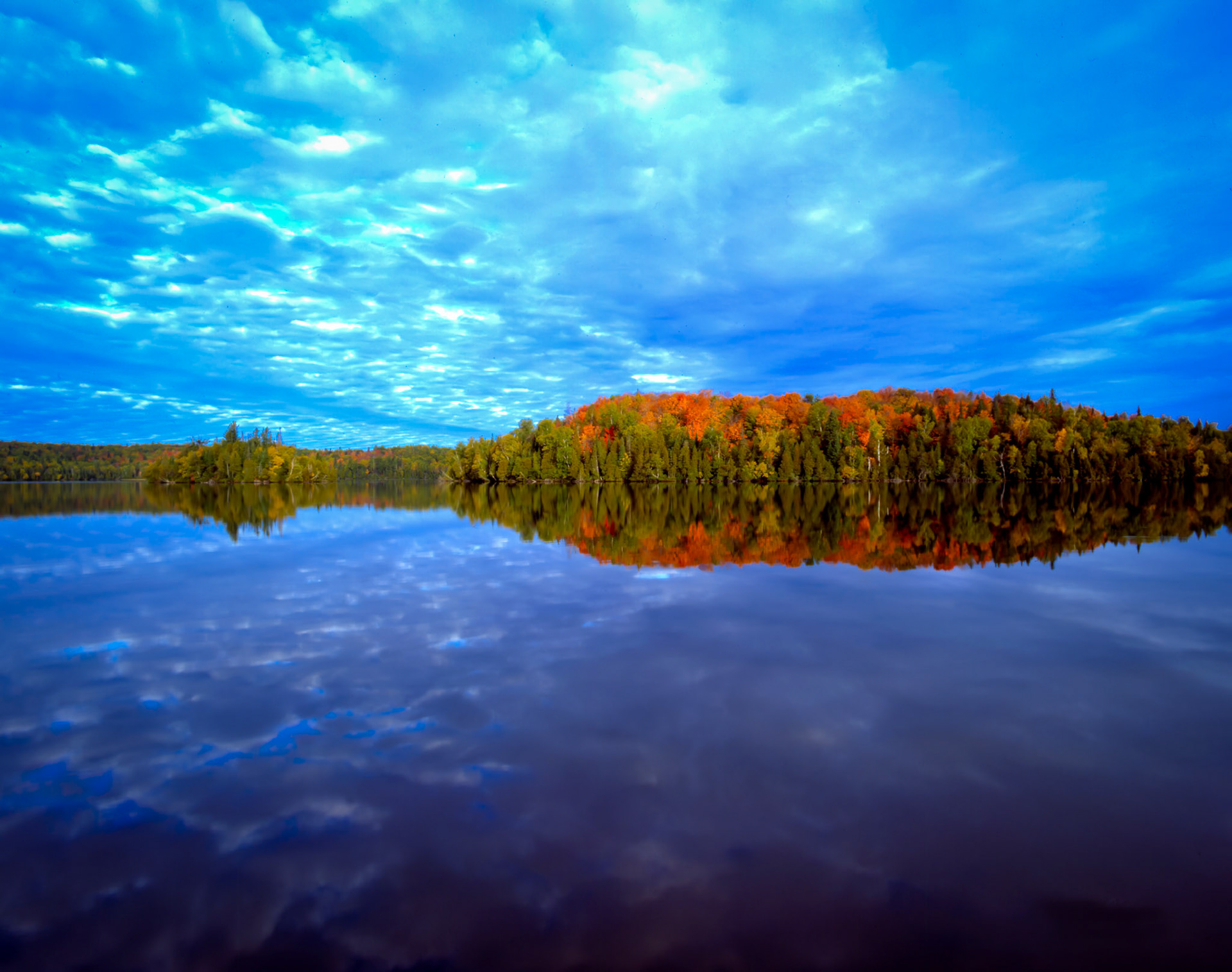September 23—Autumn Reflection—With the autumnal equinox behind us (September 23), the hours of darkness are now longer than daylight, and the cool nights of late September lead to rapidly changing colors and calm waters.The ridges along Nine Mile Lake near the Boundary Waters' reflected colors also reflect the beauty of God's creation in the Northland. Thus, nature reveals God in a small way and gives us hope for what lies ahead.Hope in Christ!For now, we see in a mirror dimly but then face to face. Now I know in part; then I shall know fully, even as I have been fully known. 1 Corinthians 13:12