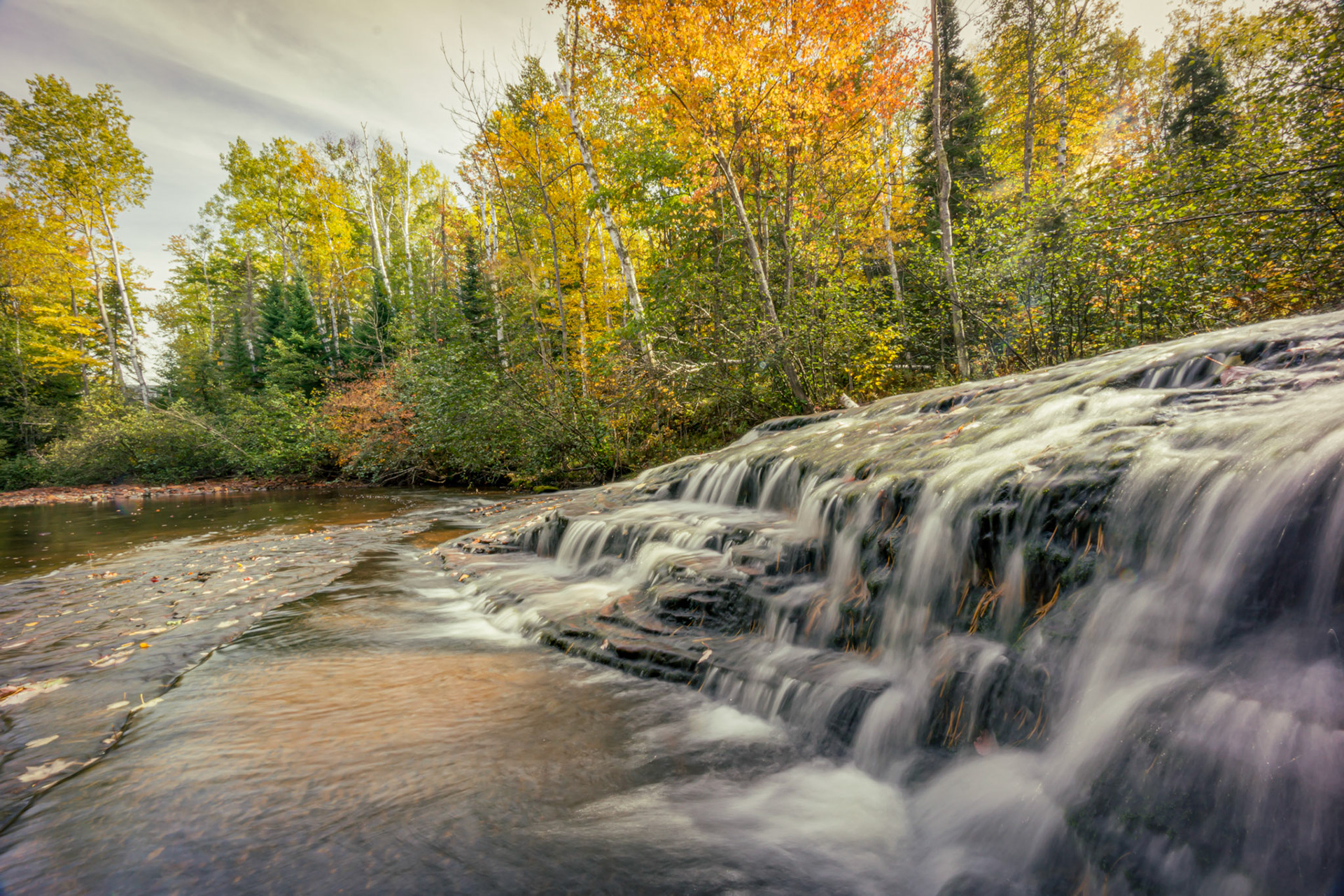 October 25 - Autumn FallsAs October draws to a close, the gentle, golden light and the whispering leaves stir memories of days gone by and the promise of brighter days ahead. Late autumn, a season of rest and reflection, is a precious gift.Near the Temperance River's headwaters, the shallow falls reflect the season with light and colors while the water's soft sound quiets the soul.Come to me, all who labor and are heavily laden, and I will give you rest." Matthew 11:28