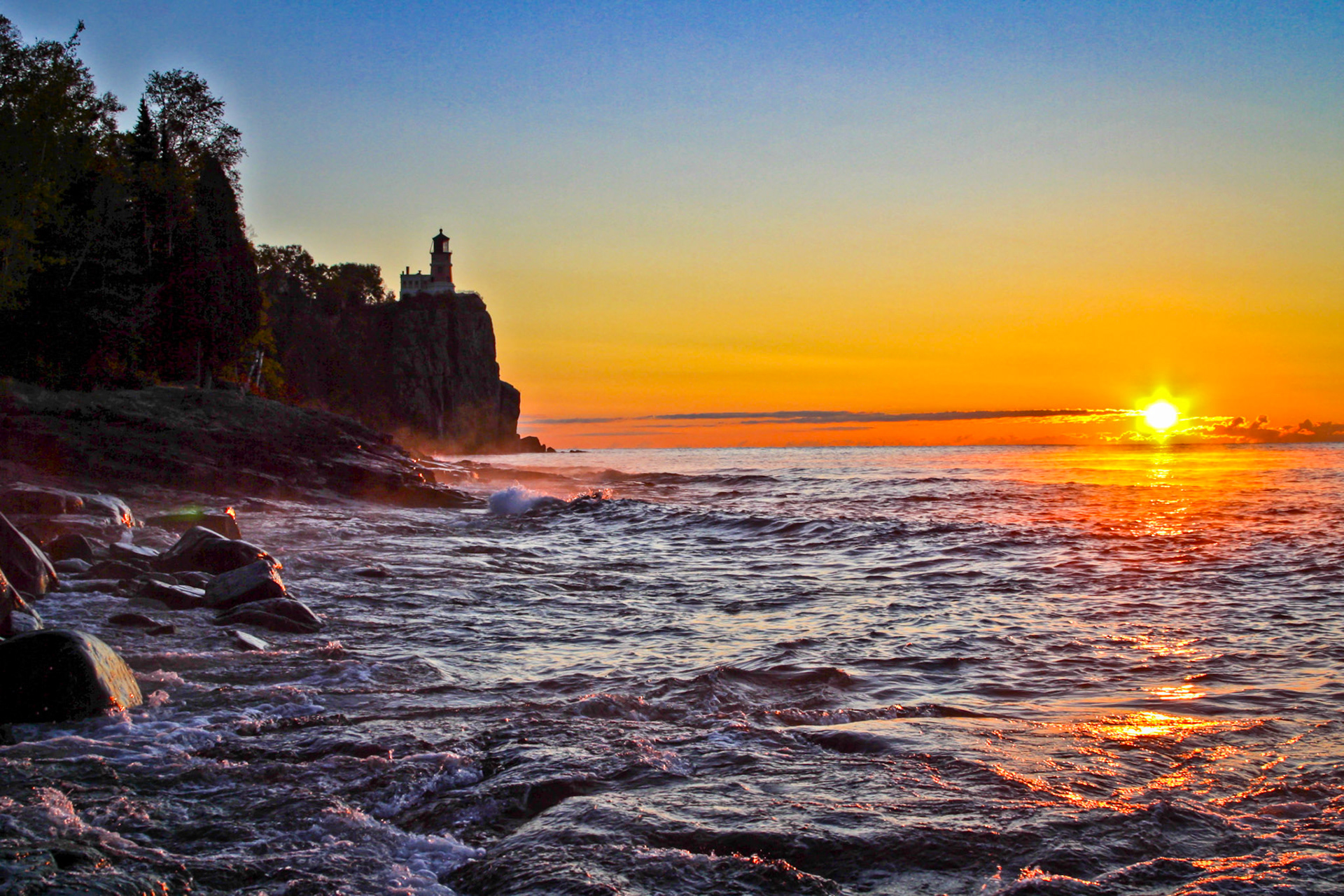 October 16—First Light—Mid-October brings cool temperatures and clear skies to the Lake Superior Region. This October morning, Split Rock Lighthouse stands sentinel over Lake Superior as it has for over a century.As the eyelids of creation open to a new day, a beautiful sunrise resets our view of life and sets us on a firm foundation, much like Split Rock Lighthouse.This is the message we have heard from him and proclaim to you, that God is light, and in him is no darkness. 1 John 1:5